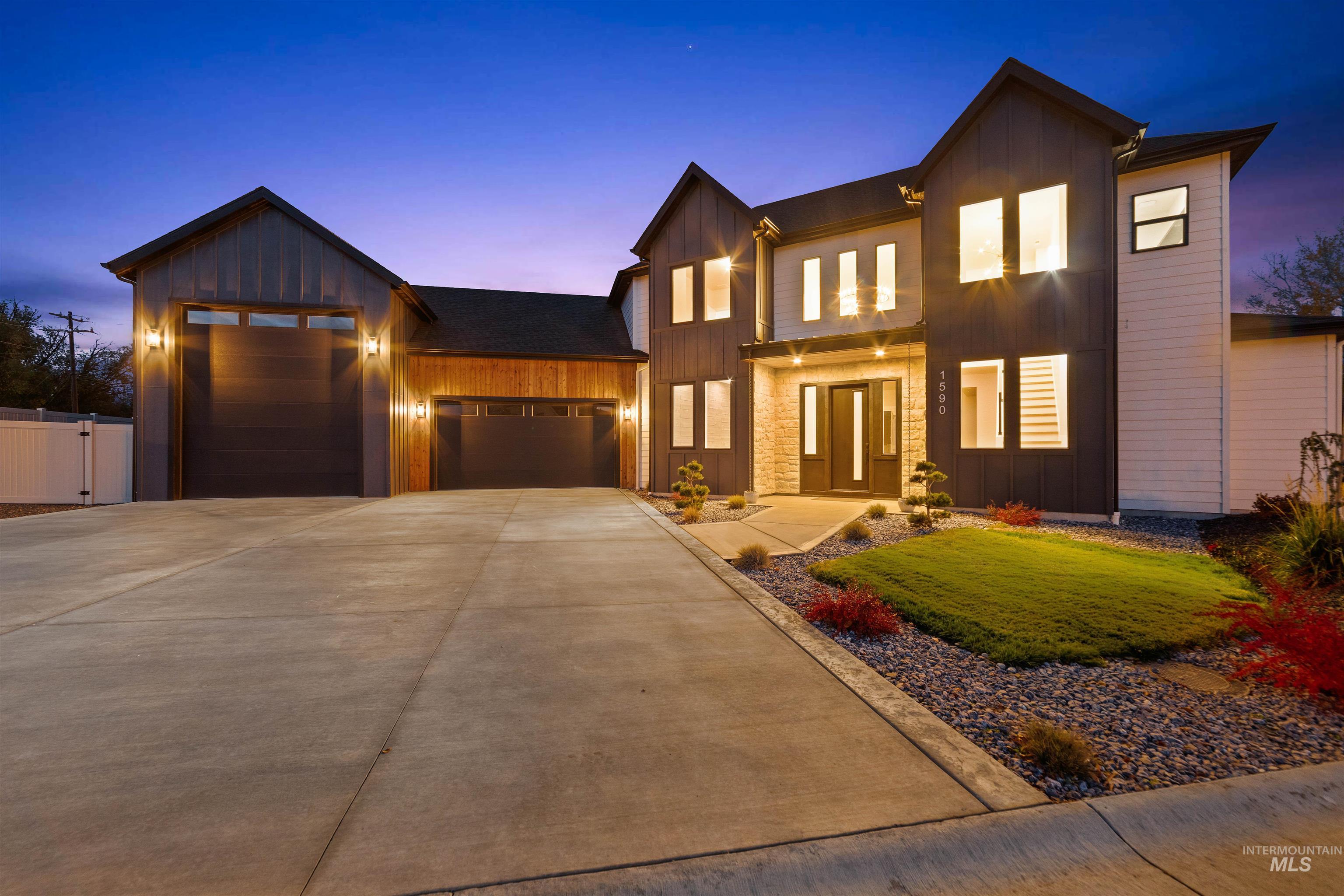 View of front of house with board and batten siding, an attached garage, concrete driveway, and a front lawn