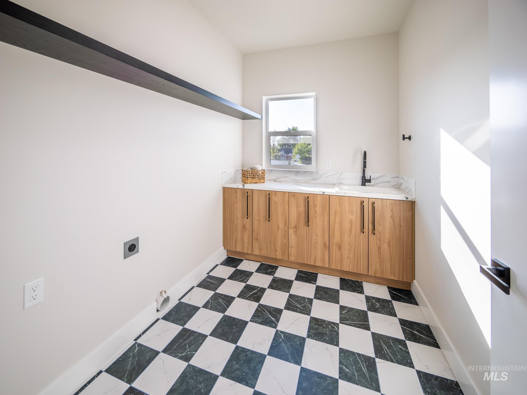 Washroom with electric dryer hookup and dark flooring