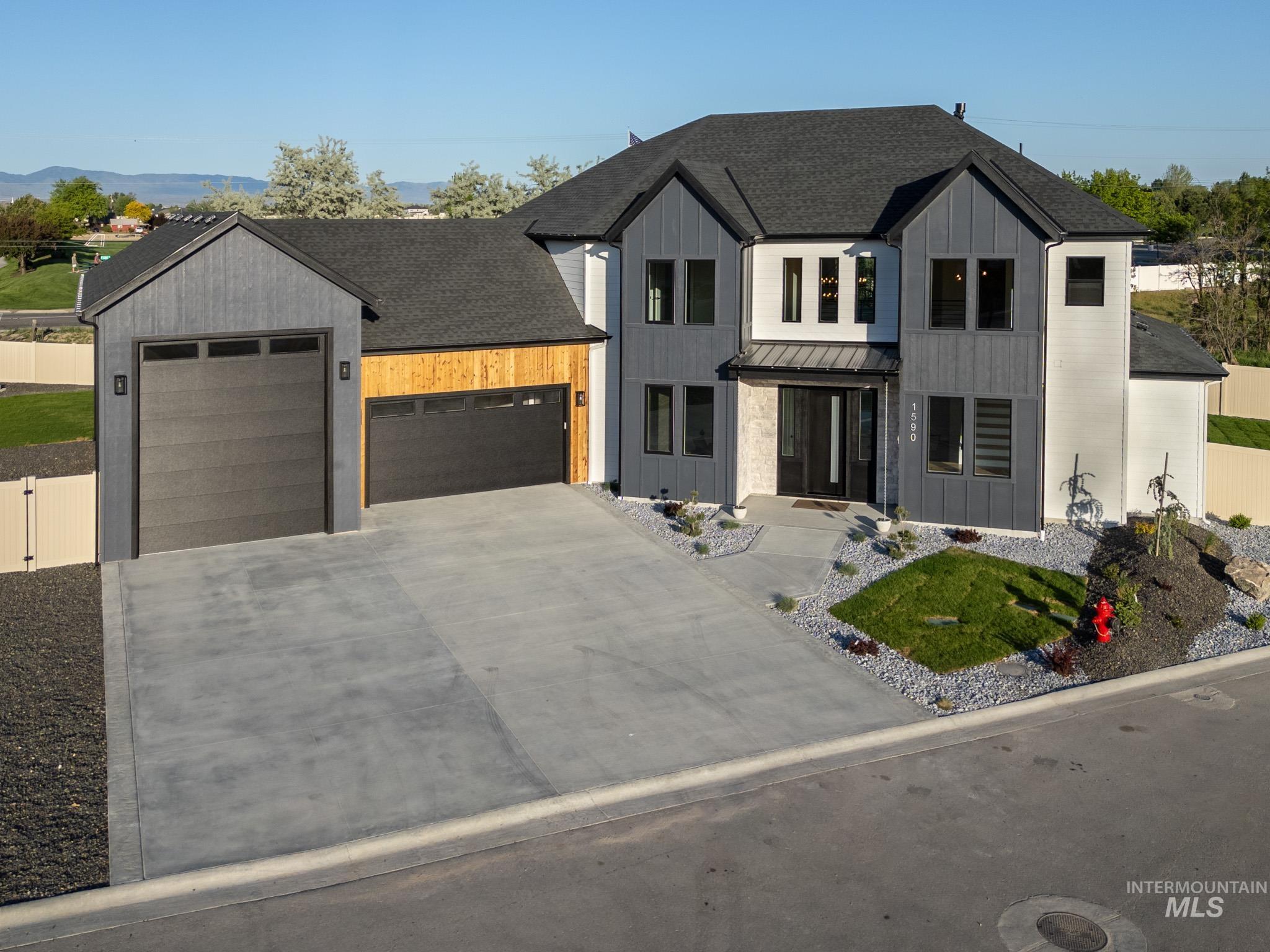 Modern farmhouse featuring roof with shingles, an attached garage, board and batten siding, driveway, and a standing seam roof