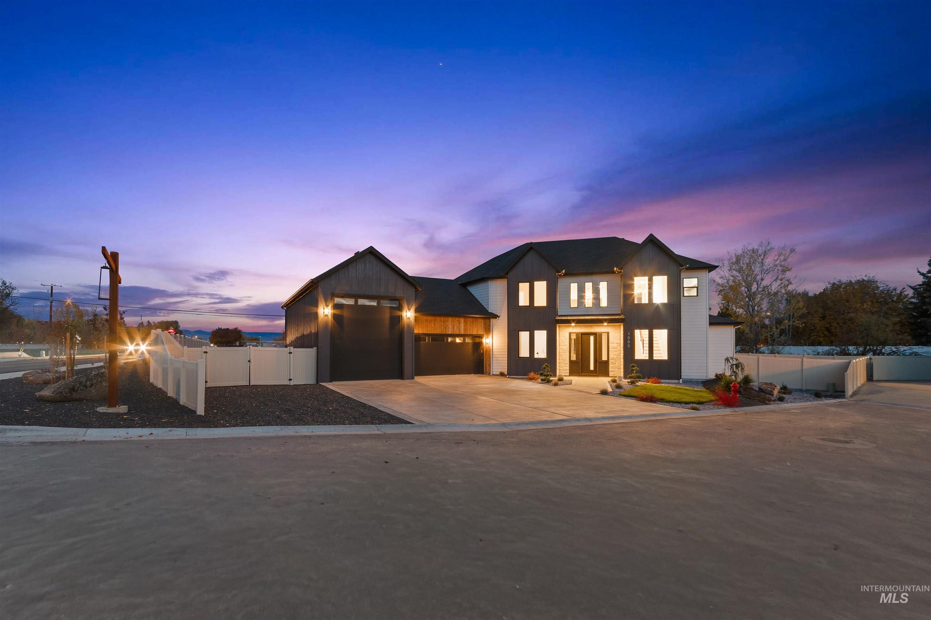 Modern inspired farmhouse featuring driveway, a garage, board and batten siding, and a gate