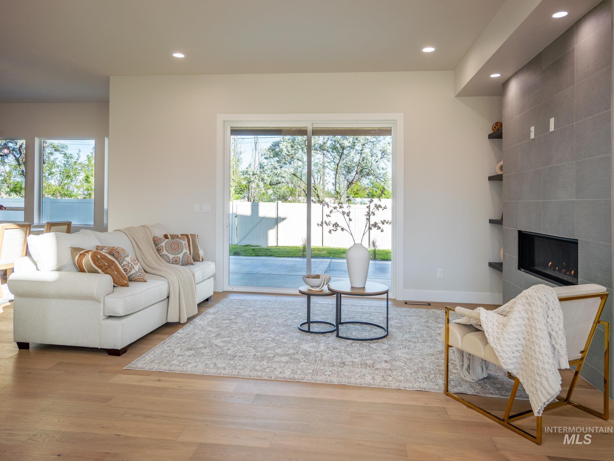 Living area featuring recessed lighting, a tiled fireplace, and light wood finished floors