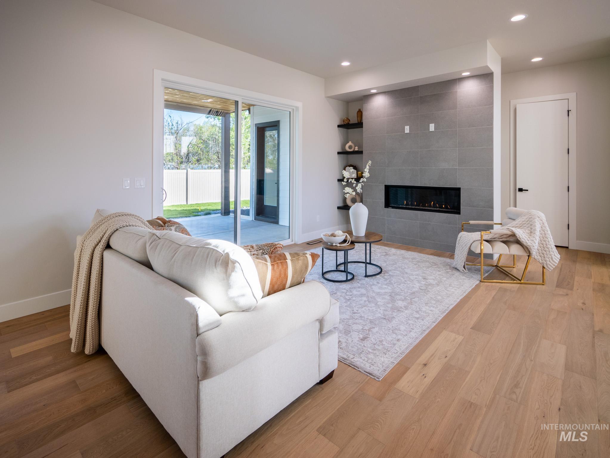 Living area featuring a tile fireplace, recessed lighting, and wood finished floors