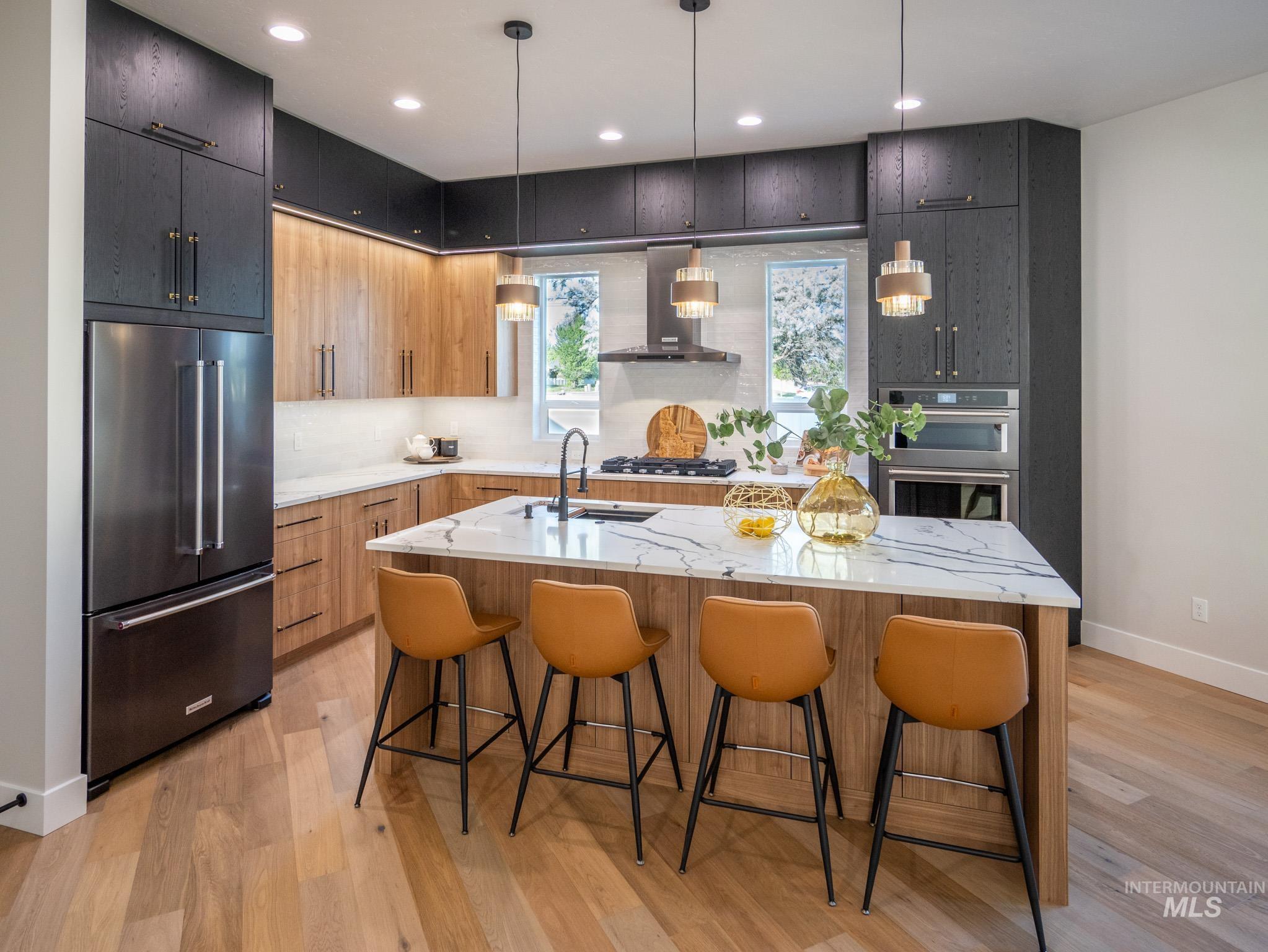 Kitchen featuring appliances with stainless steel finishes, light stone counters, pendant lighting, a kitchen breakfast bar, and recessed lighting