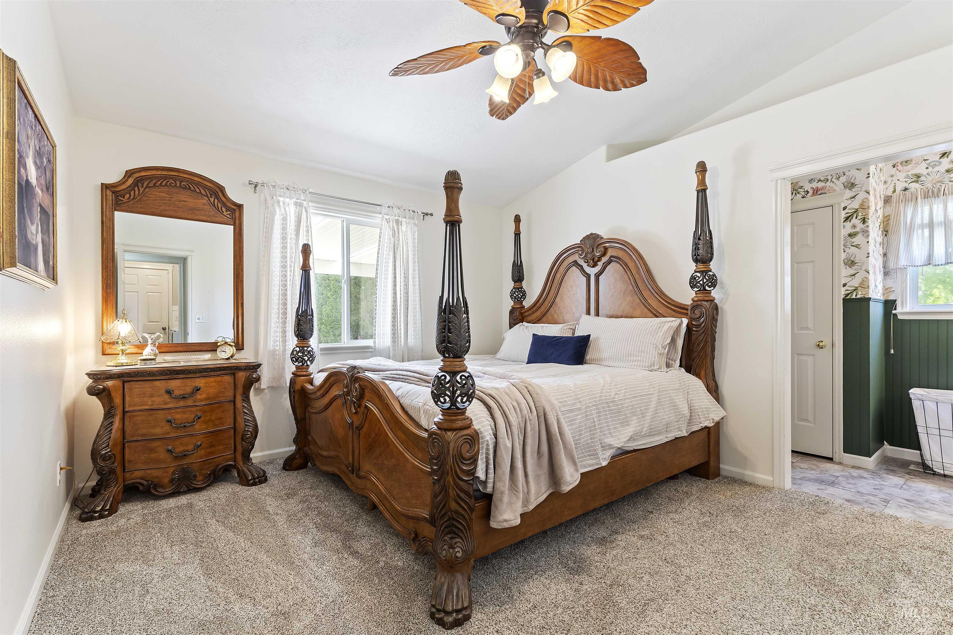 Bedroom with light carpet, ceiling fan, and lofted ceiling