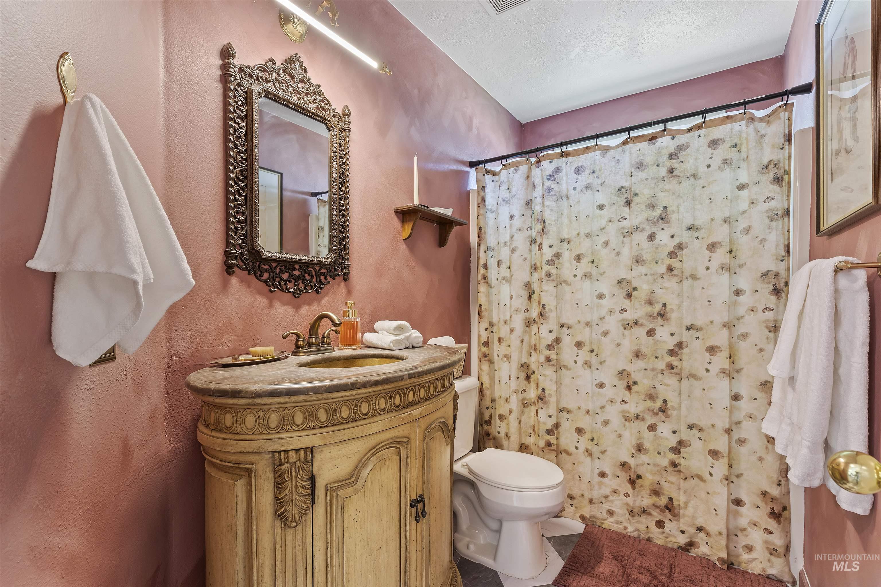 Full bath with a shower with shower curtain, vanity, a textured wall, and a textured ceiling