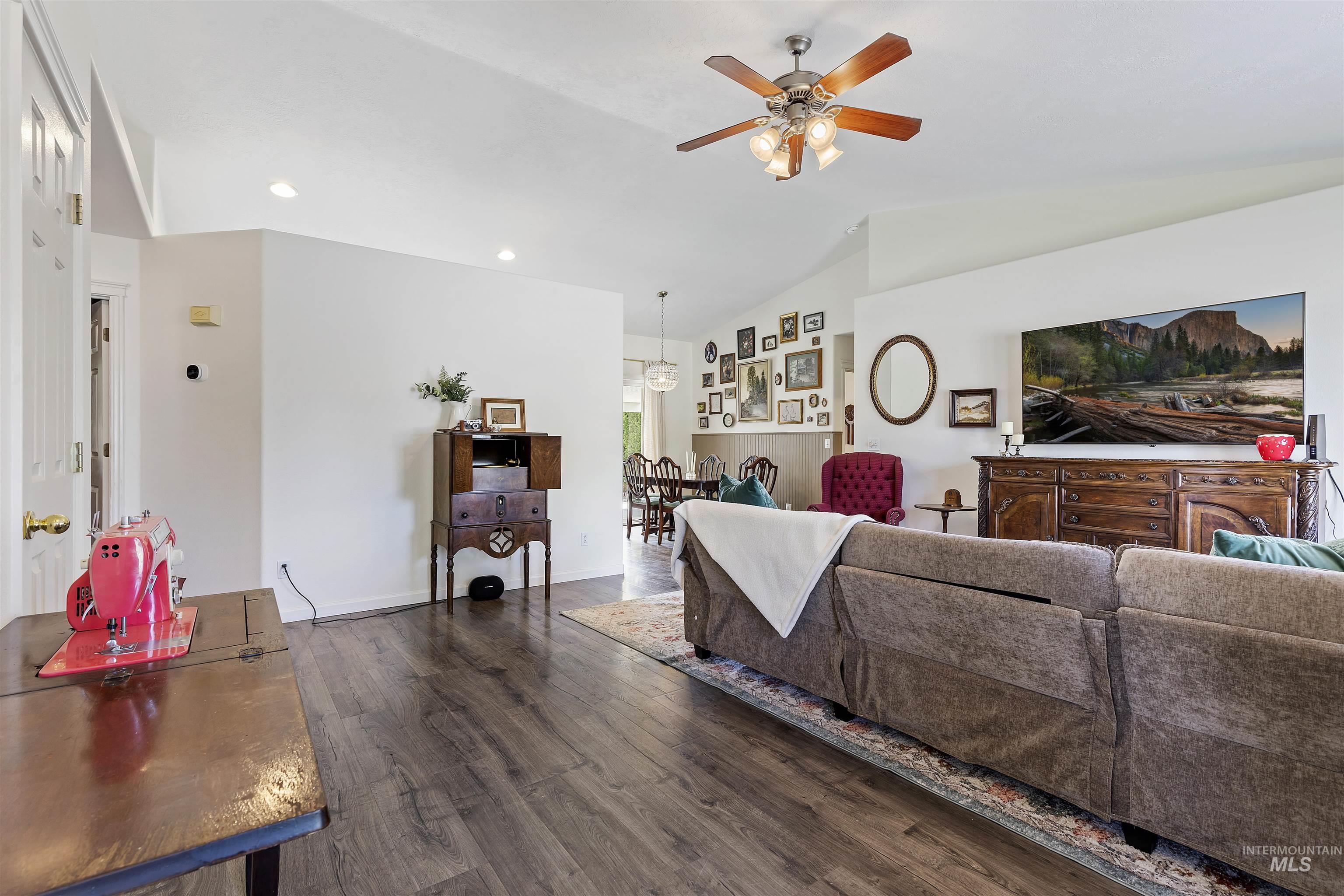 Living room featuring lofted ceiling, dark wood-style floors, a ceiling fan, and recessed lighting