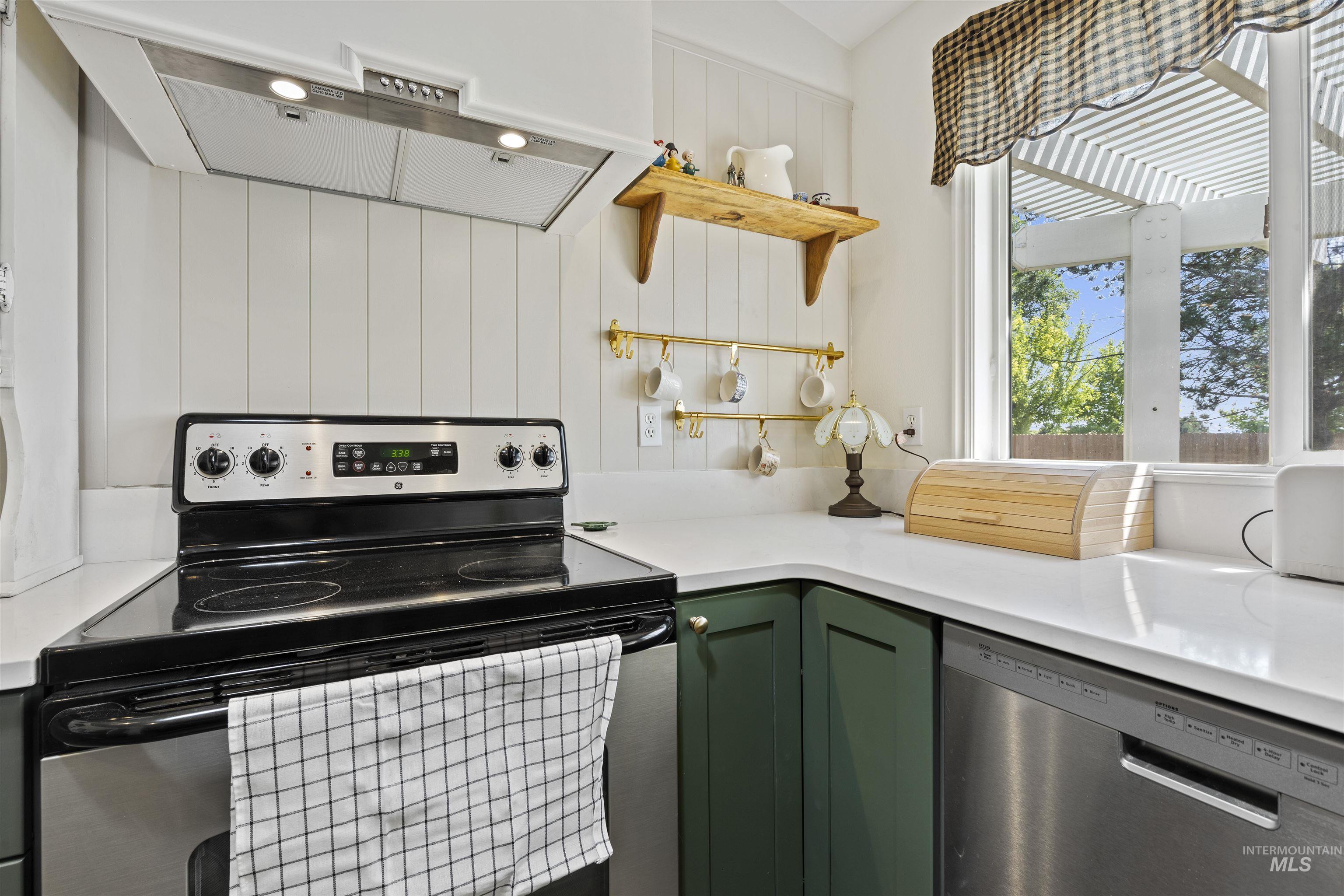 Kitchen with under cabinet range hood, stainless steel appliances, green cabinetry, and open shelves