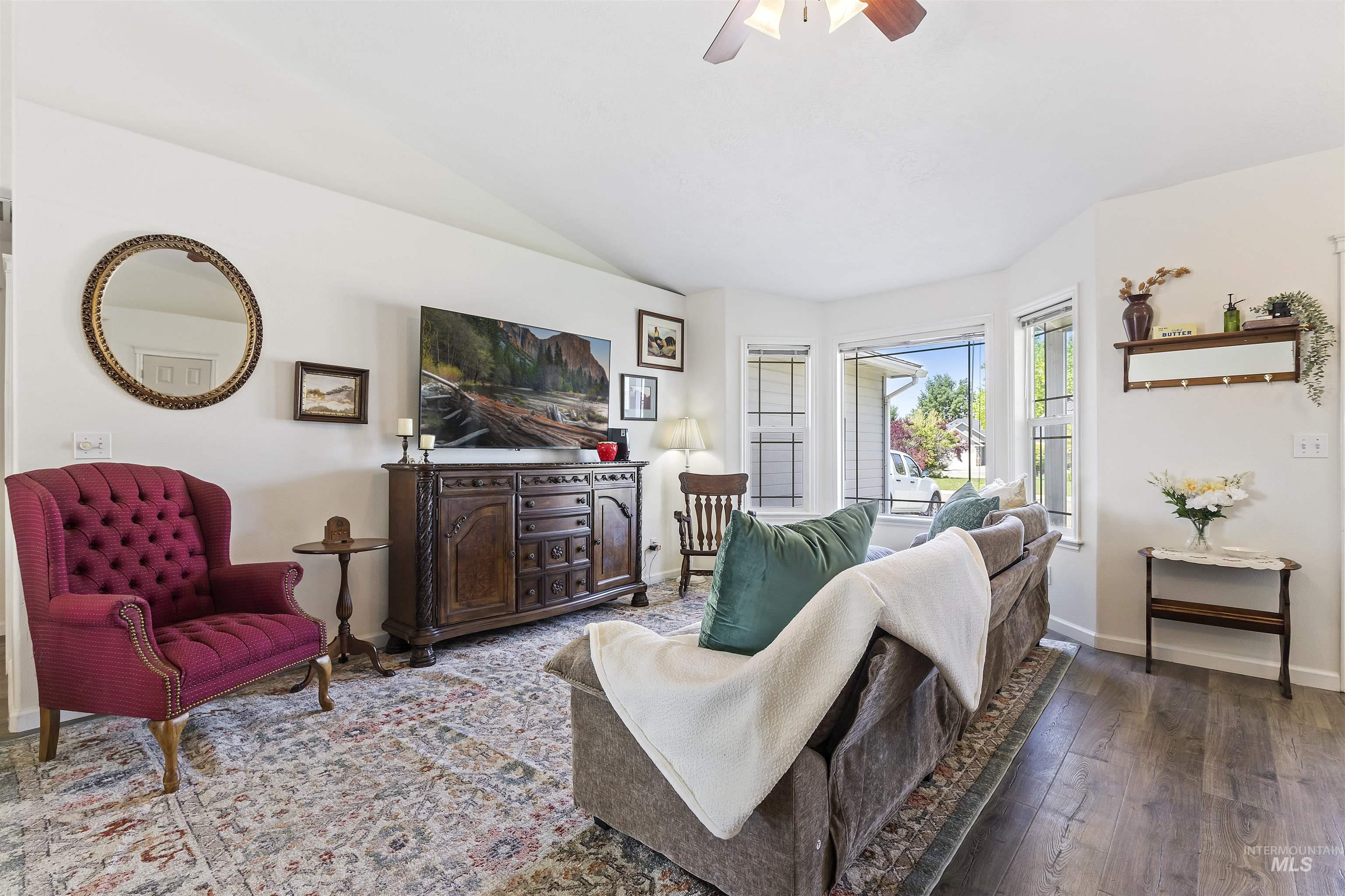 Living area with hardwood / wood-style floors, a ceiling fan, and vaulted ceiling