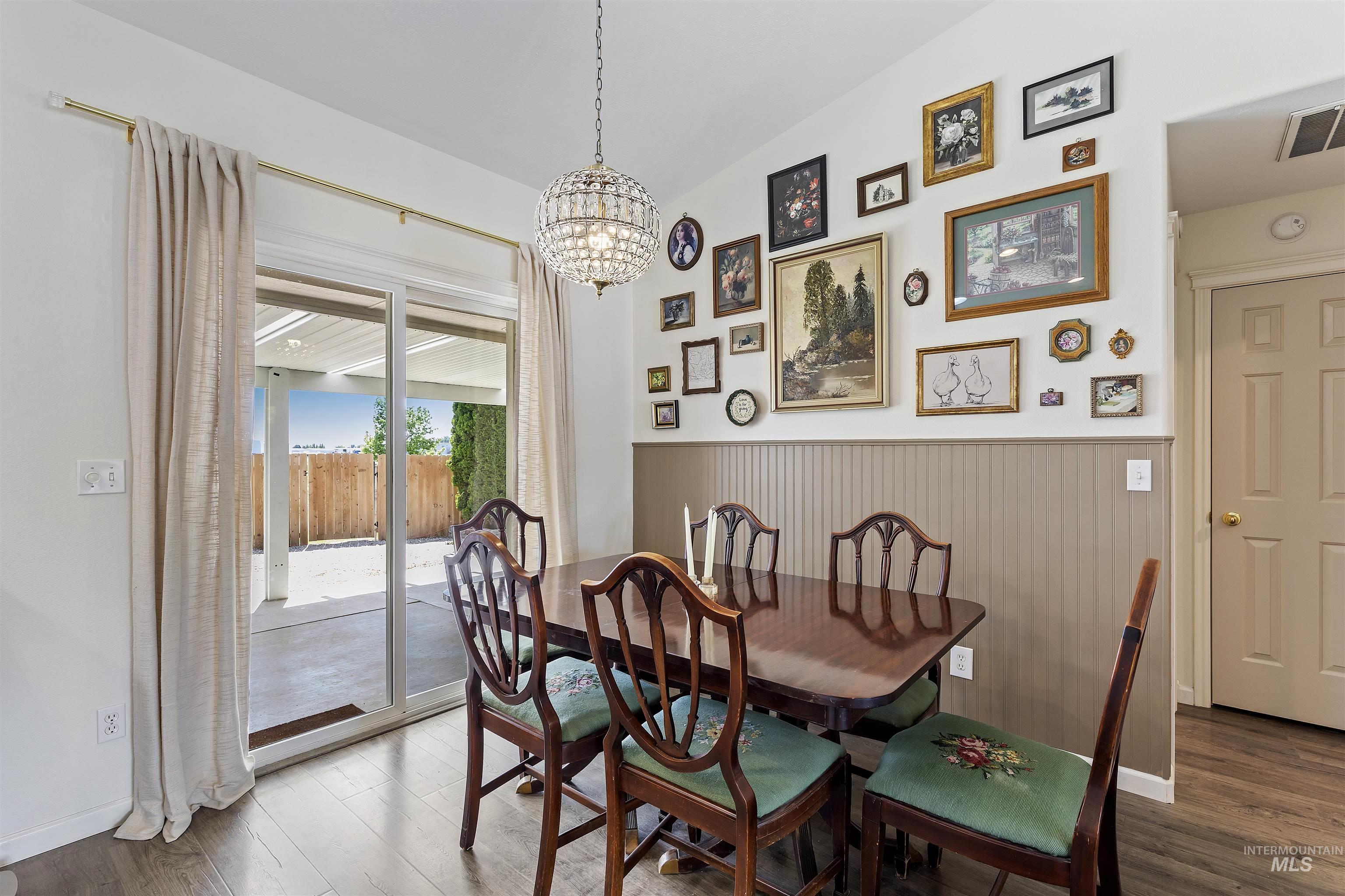 Dining area featuring a chandelier, wood finished floors, and wainscoting