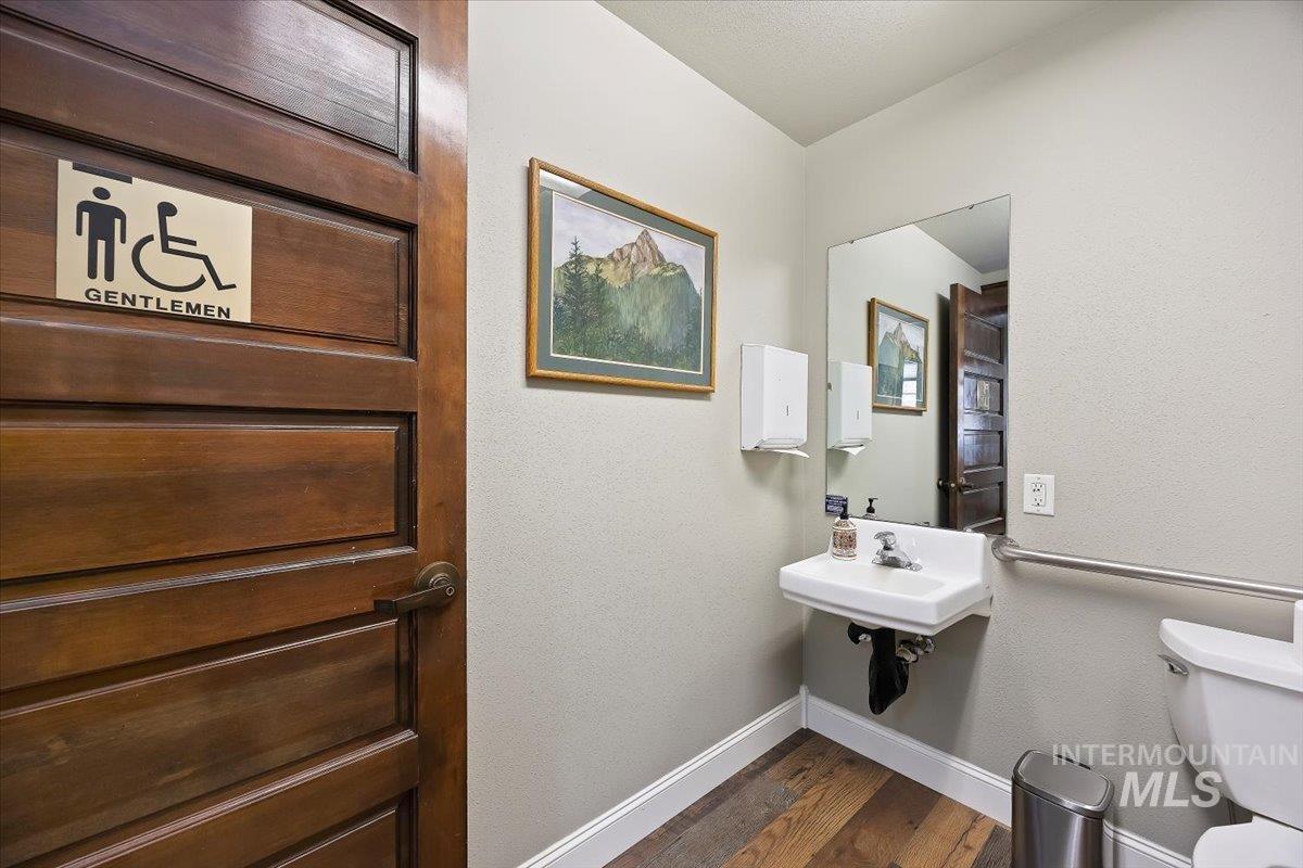 Half bathroom with dark wood finished floors and a textured wall
