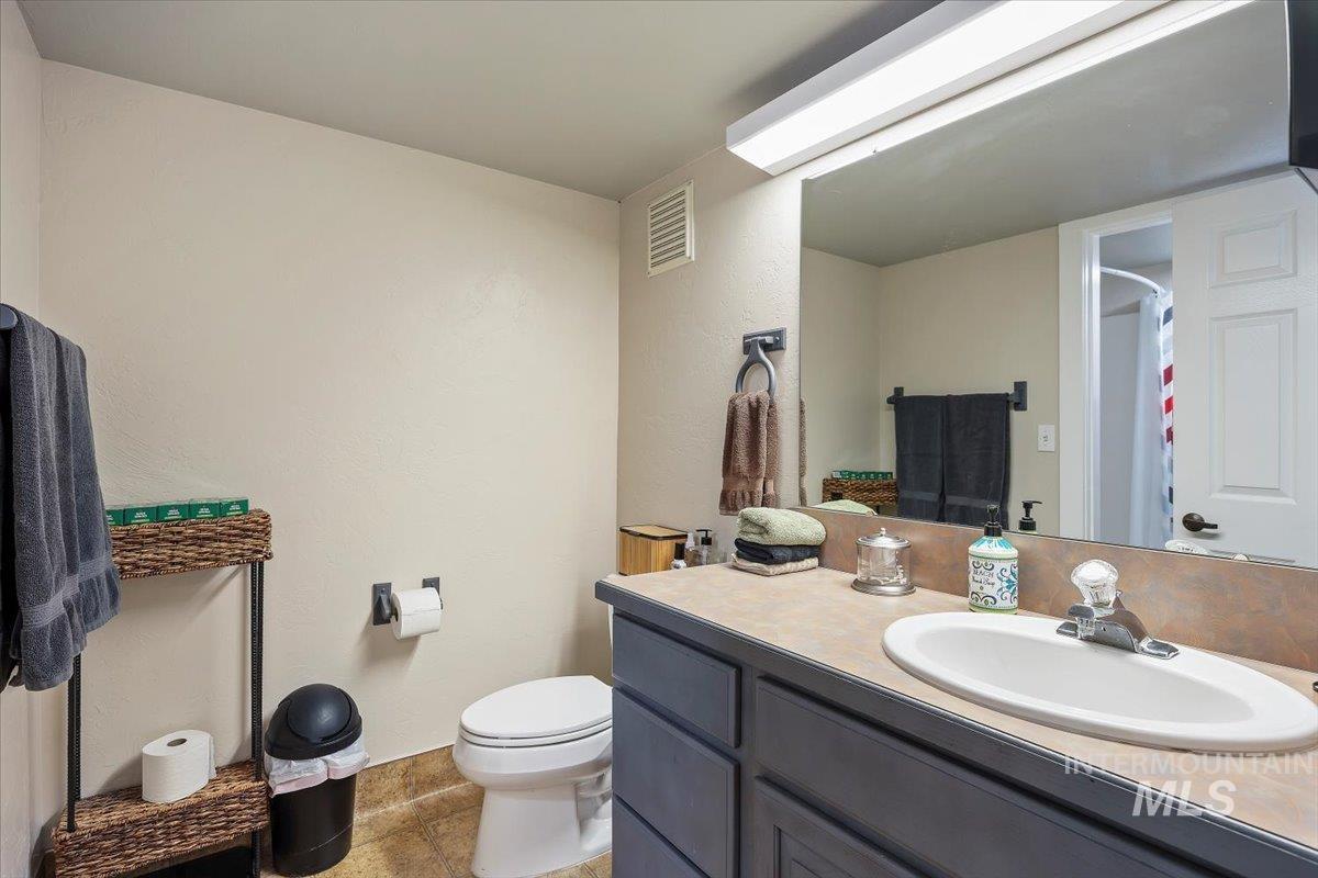Full bath featuring vanity, a shower with curtain, a textured wall, and light tile patterned floors