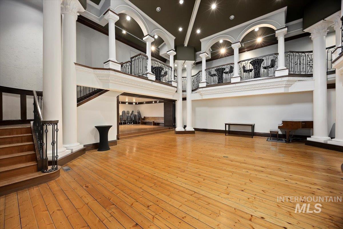 Unfurnished living room with light wood-style flooring, a towering ceiling, ornamental molding, and stairs