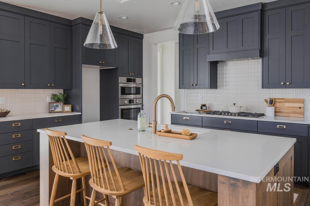 Kitchen featuring backsplash, stainless steel double oven, custom exhaust hood, a kitchen bar, and dark wood-type flooring