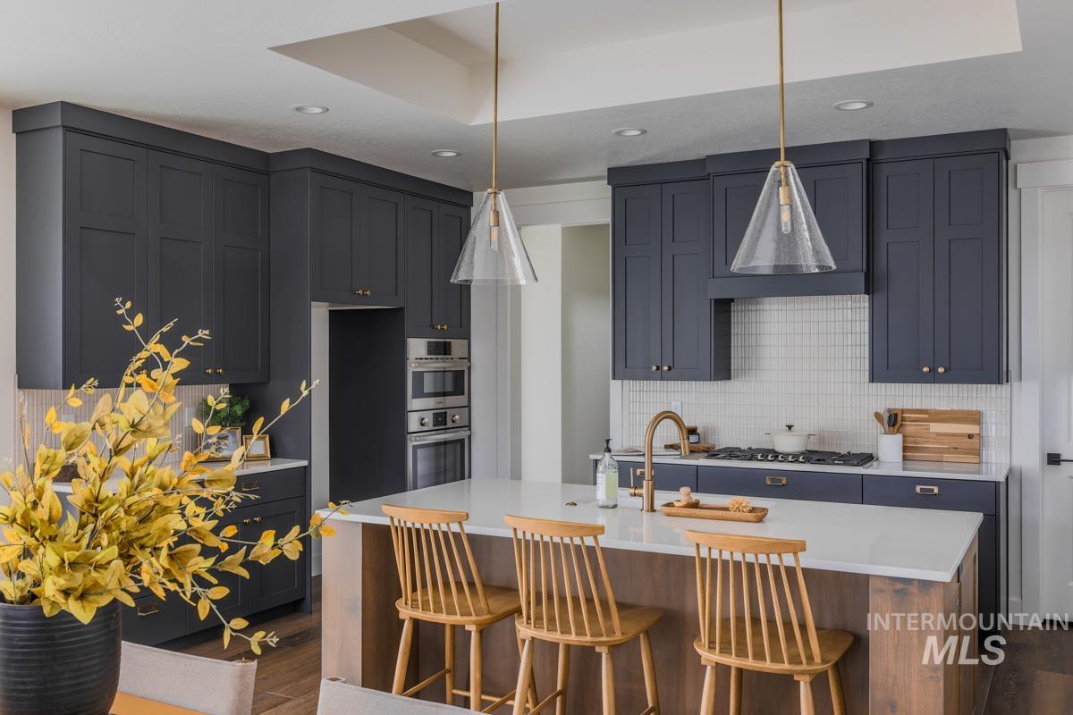 Kitchen featuring dark wood-style flooring, a kitchen island with sink, decorative light fixtures, and recessed lighting