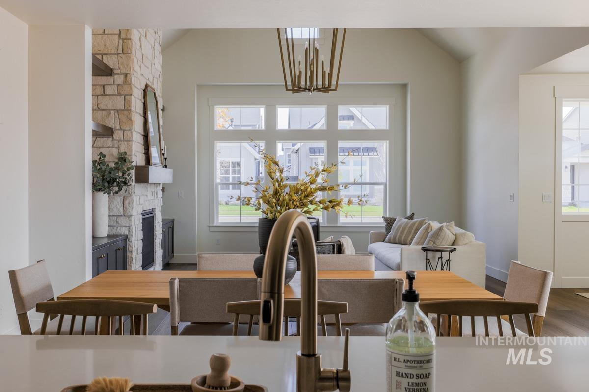 Dining room with healthy amount of natural light, wood finished floors, a stone fireplace, and a chandelier