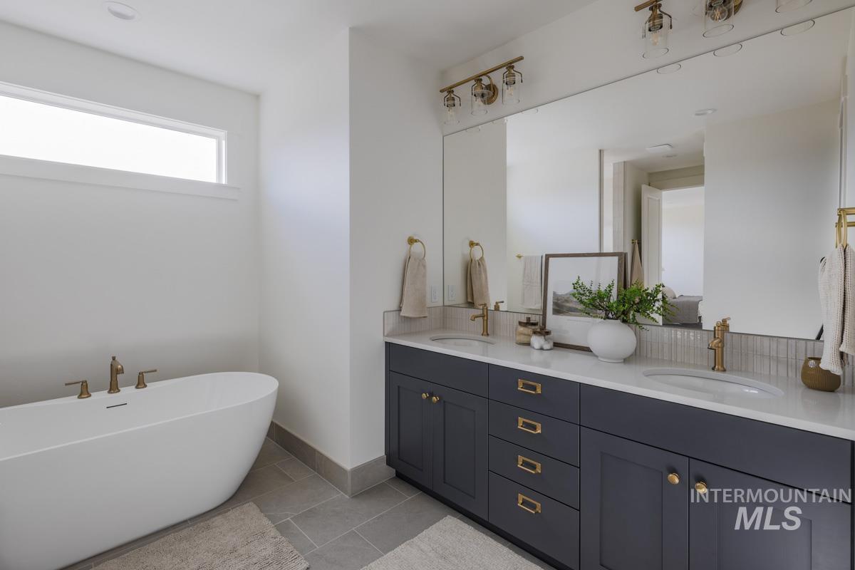 Bathroom with a freestanding tub, double vanity, and light tile patterned floors