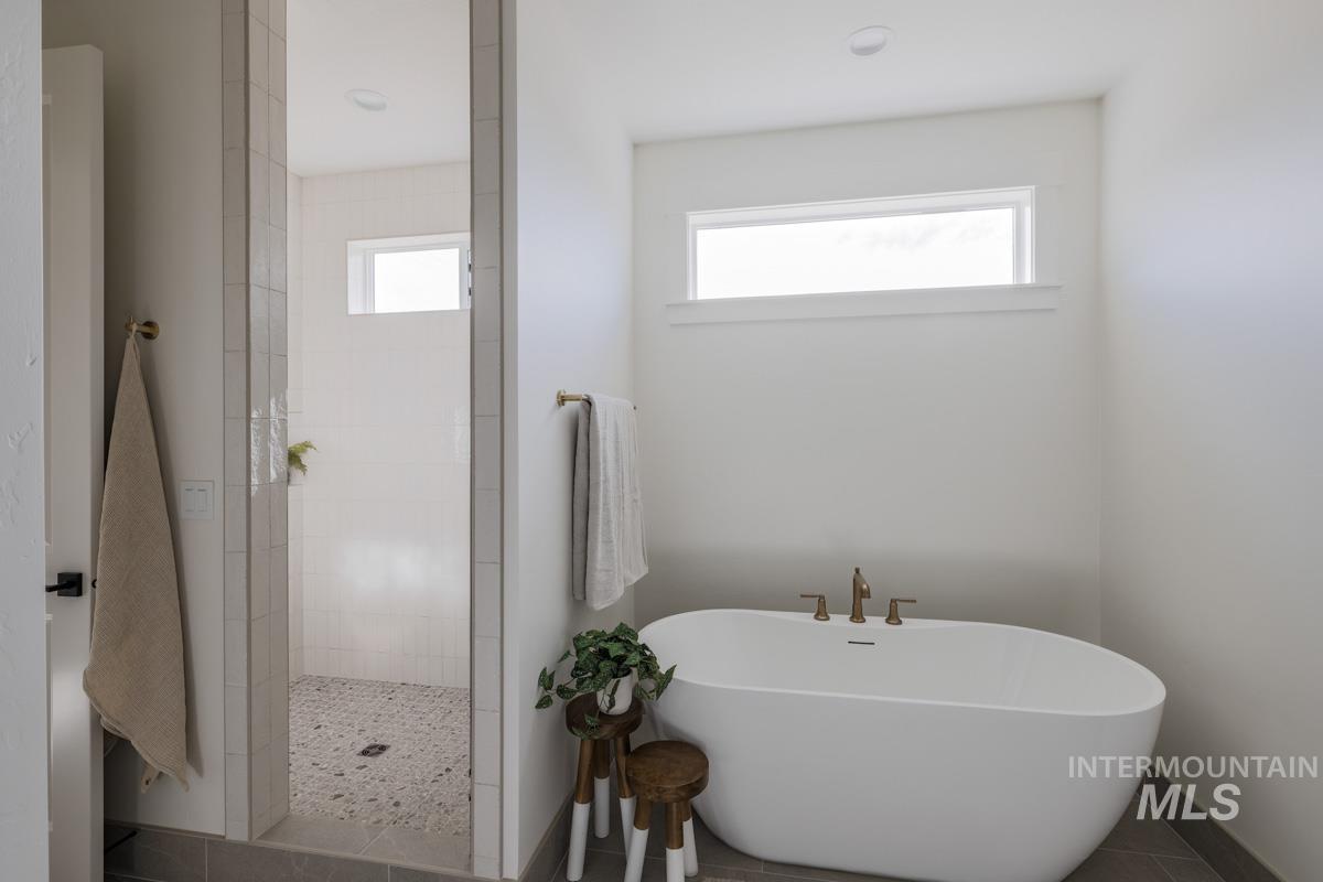 Bathroom with a walk in shower, a soaking tub, plenty of natural light, and tile patterned floors