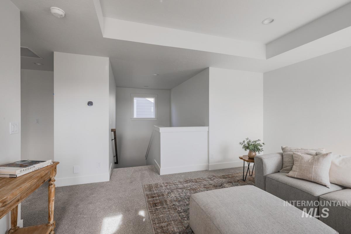 Sitting room with an upstairs landing, carpet floors, and a tray ceiling