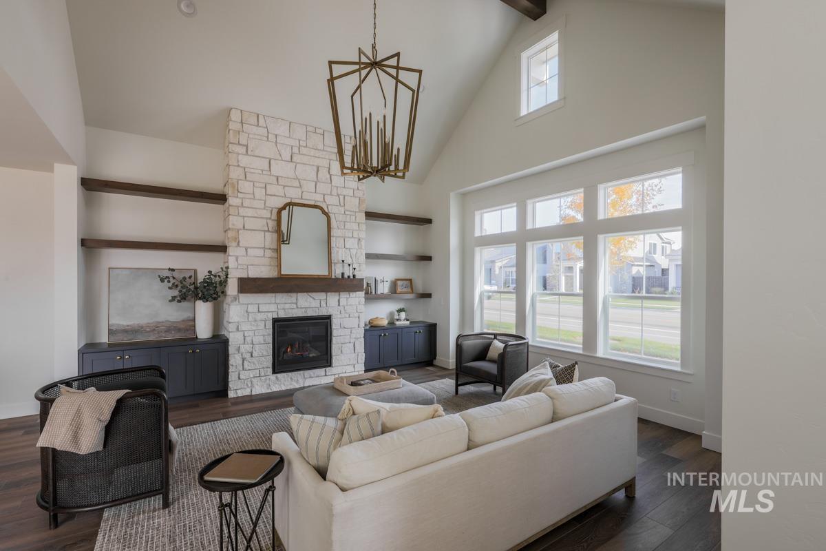 Living room with high vaulted ceiling, dark wood-style floors, a fireplace, beamed ceiling, and a chandelier