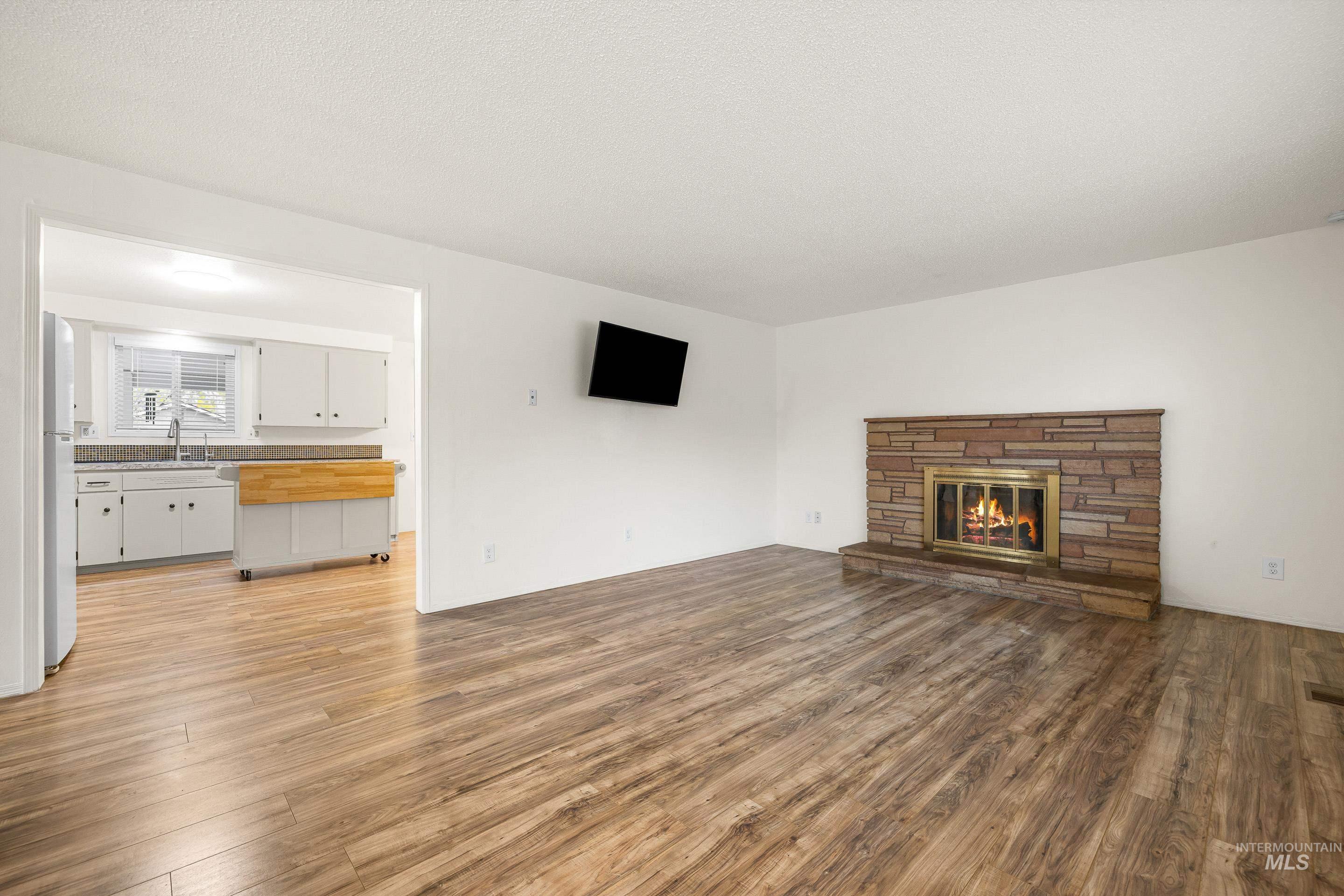 Unfurnished living room with light wood-style flooring and a stone fireplace