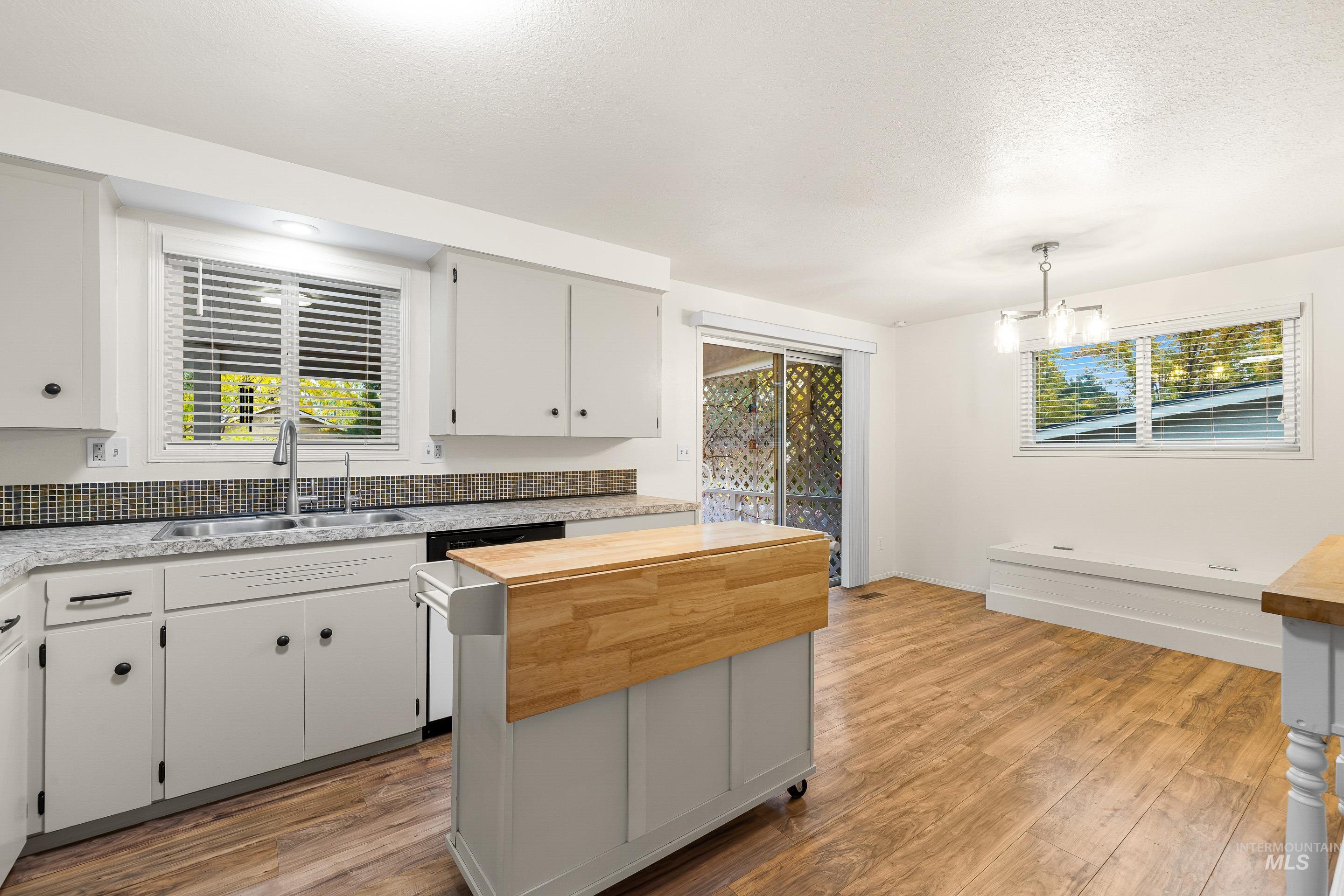 Kitchen featuring wooden counters, pendant lighting, light wood-type flooring, white cabinets, and a kitchen island