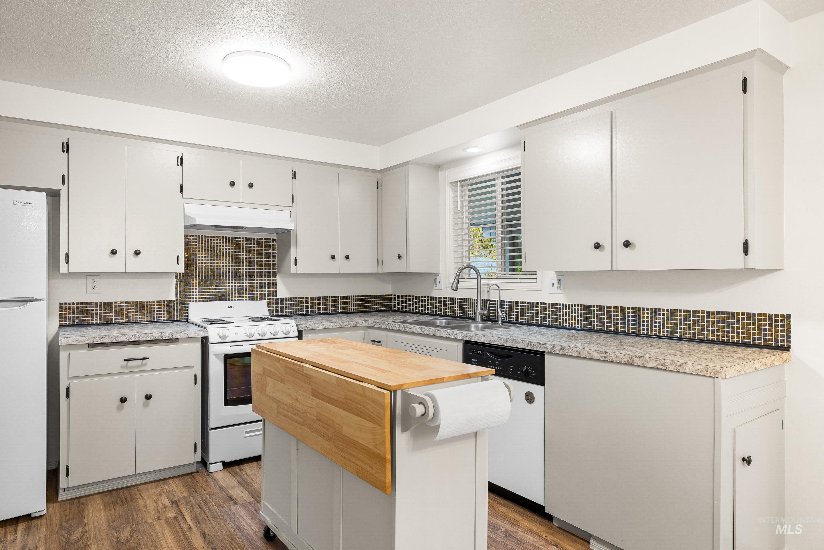 Kitchen featuring backsplash, white appliances, butcher block counters, dark wood-style flooring, and a textured ceiling