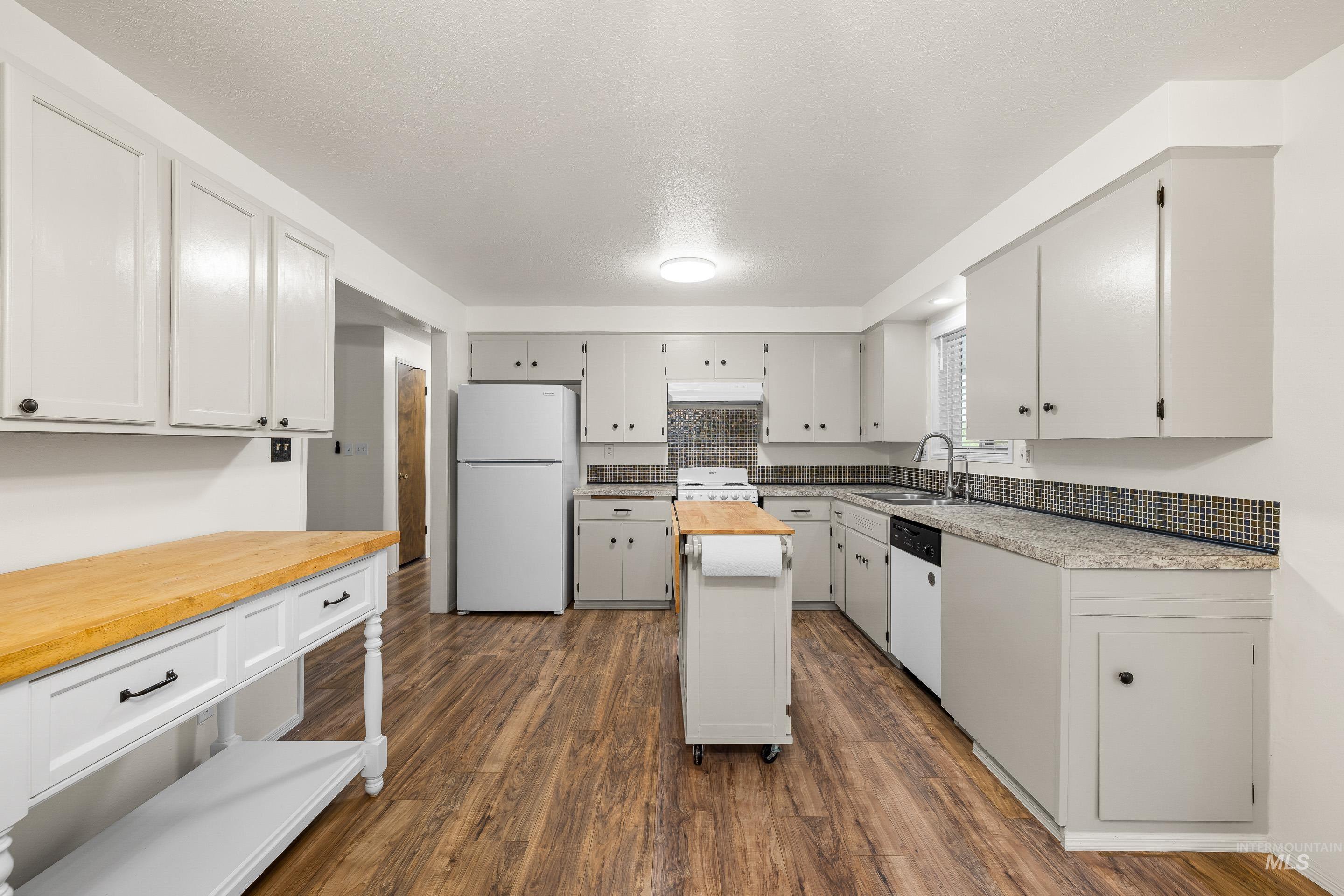 Kitchen with wooden counters, white appliances, dark wood-style flooring, premium range hood, and white cabinets