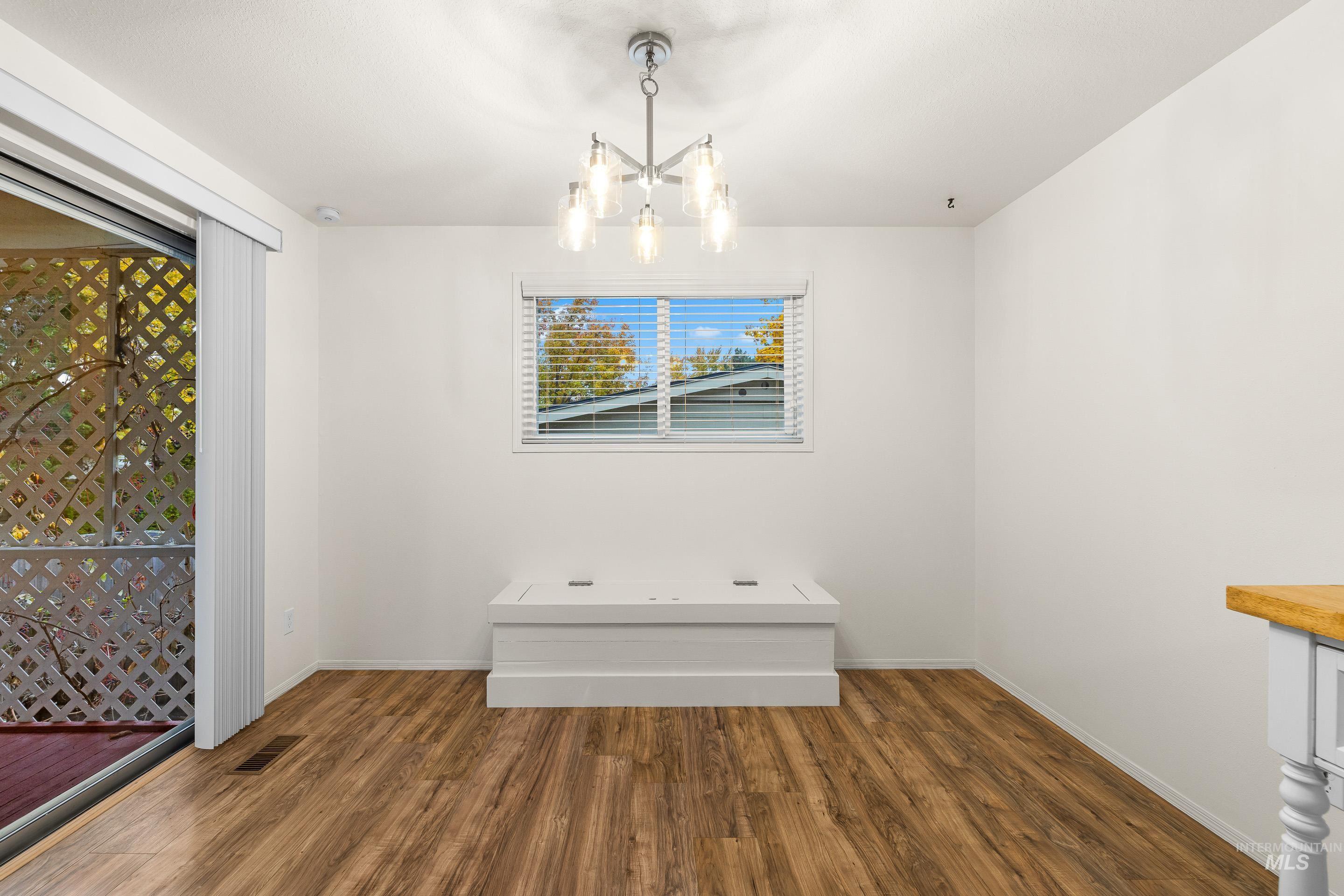 Unfurnished dining area featuring dark wood-style floors and a chandelier