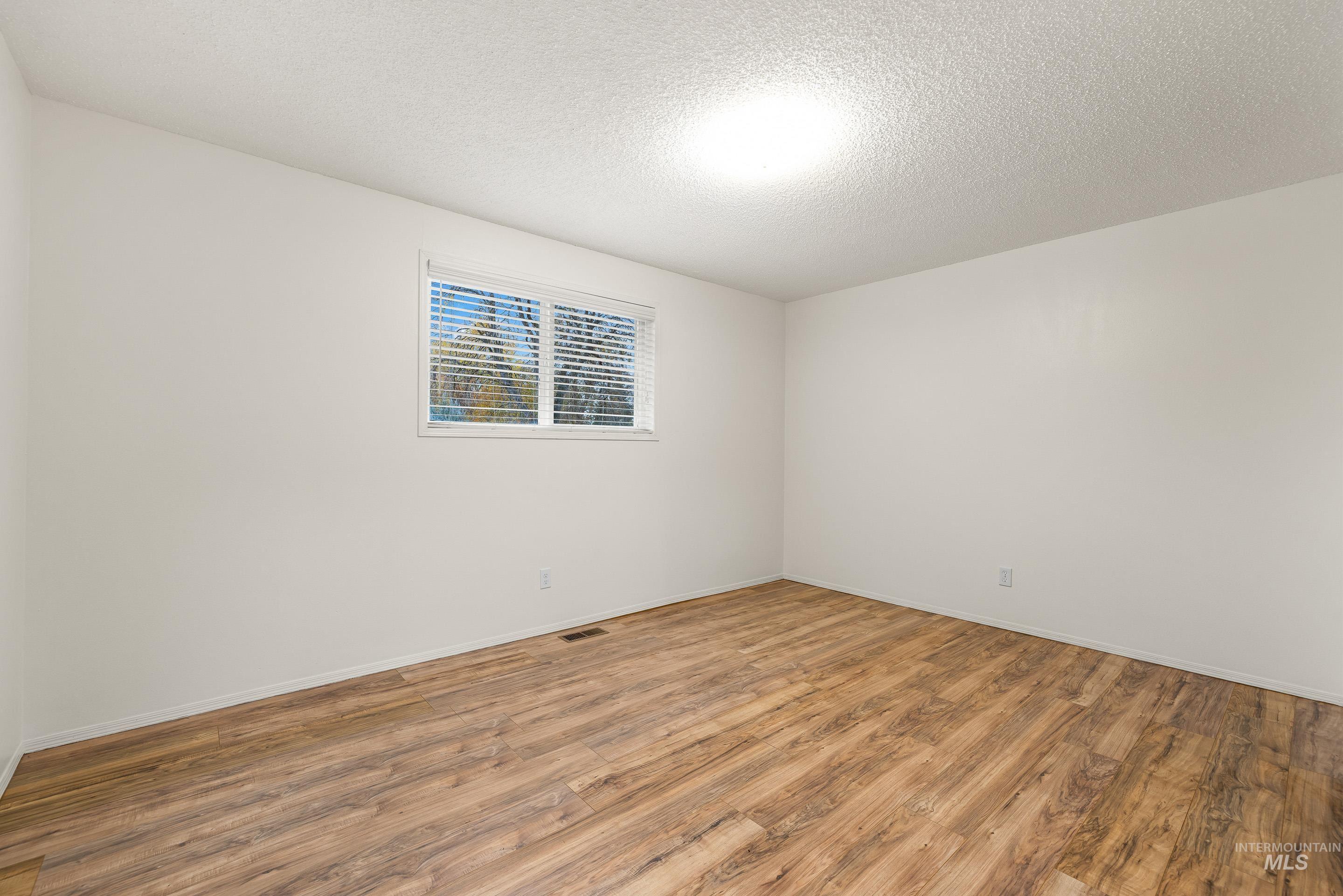 Unfurnished room featuring wood finished floors and a textured ceiling