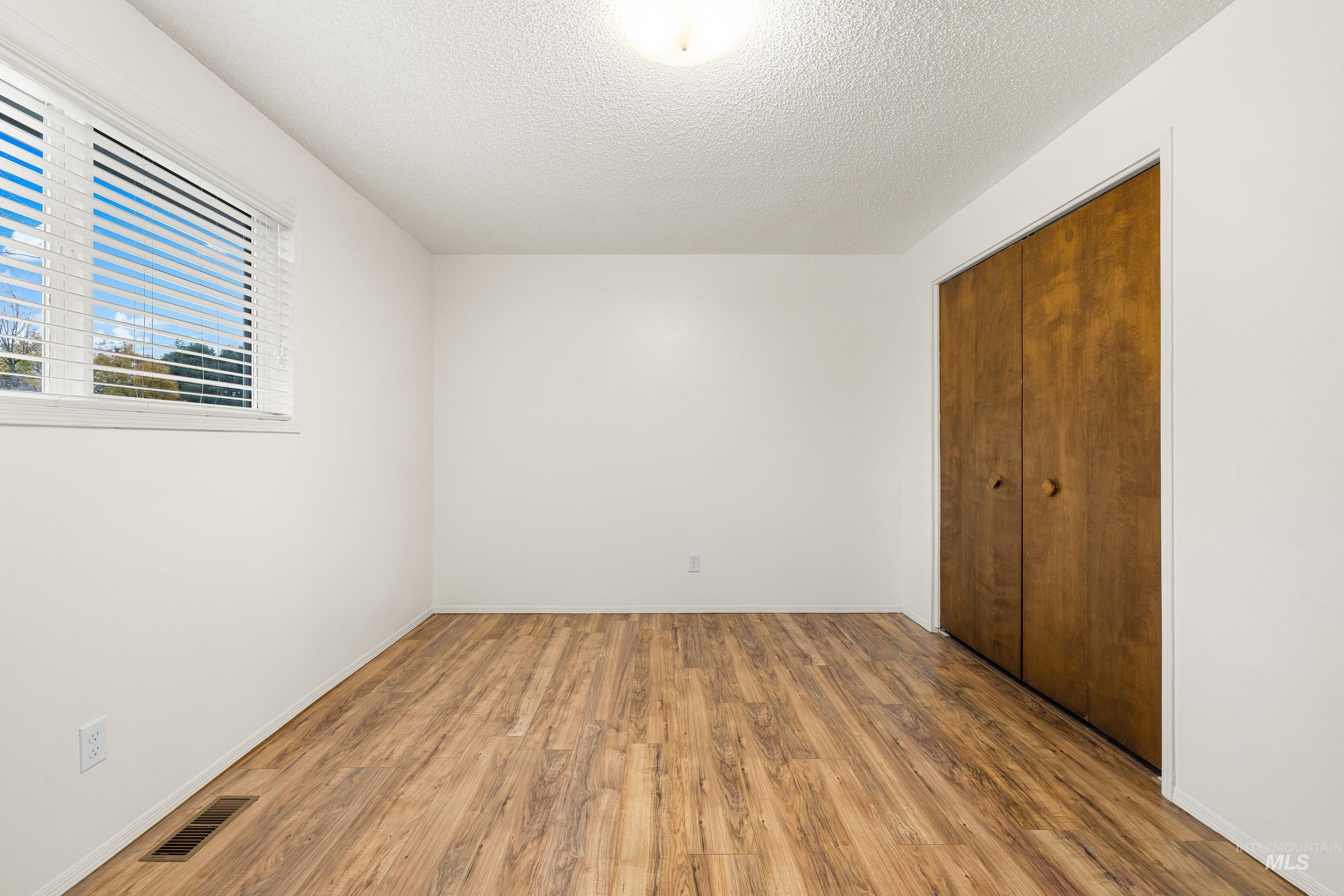 Unfurnished bedroom featuring a closet, a textured ceiling, and wood finished floors