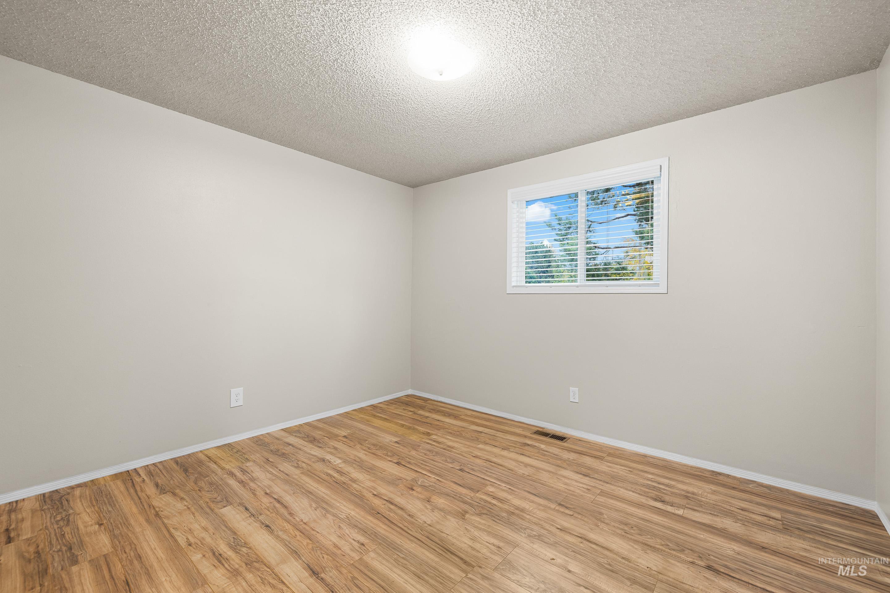 Spare room with a textured ceiling and light wood-style flooring