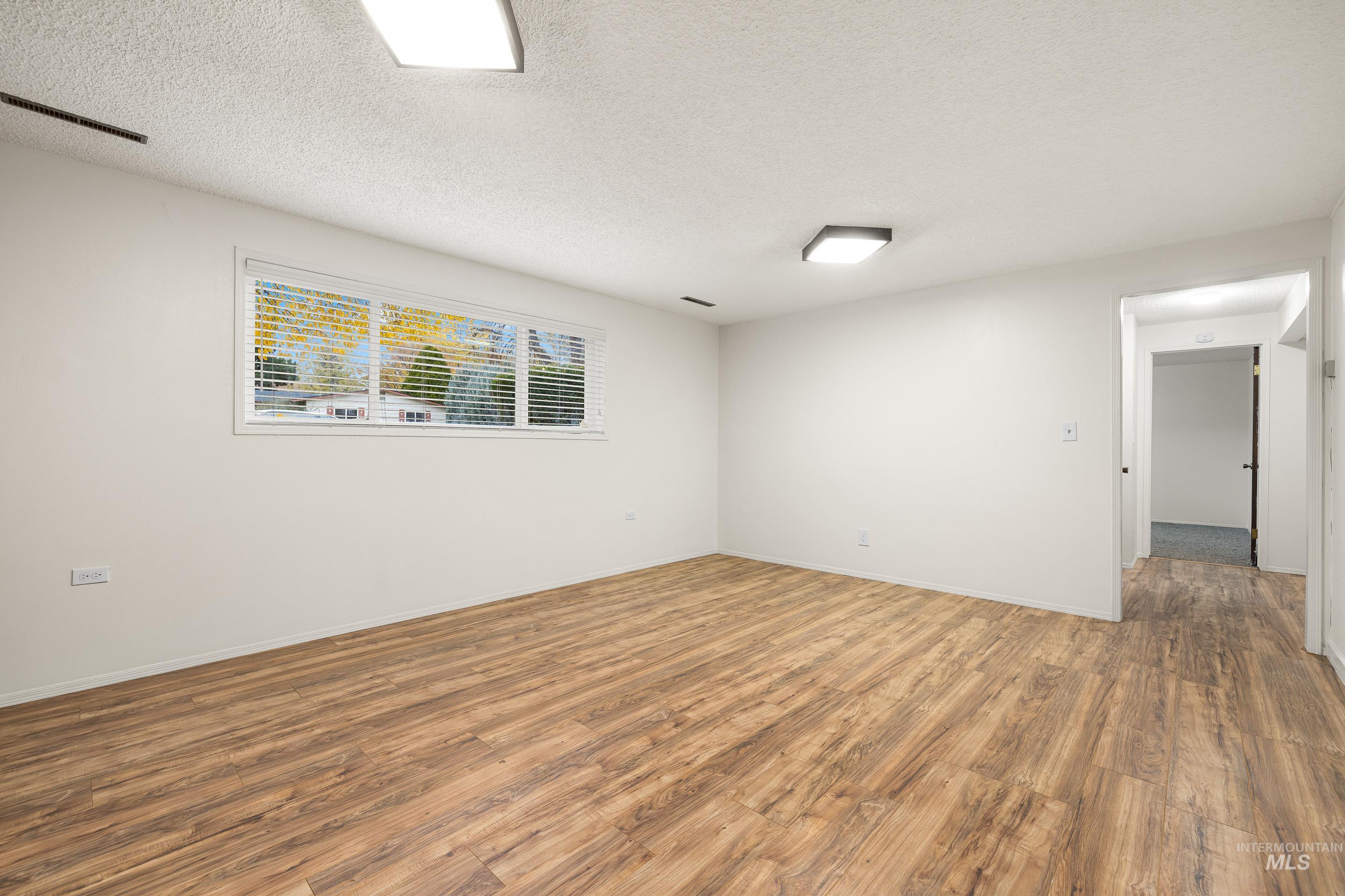 Unfurnished room featuring wood finished floors and a textured ceiling