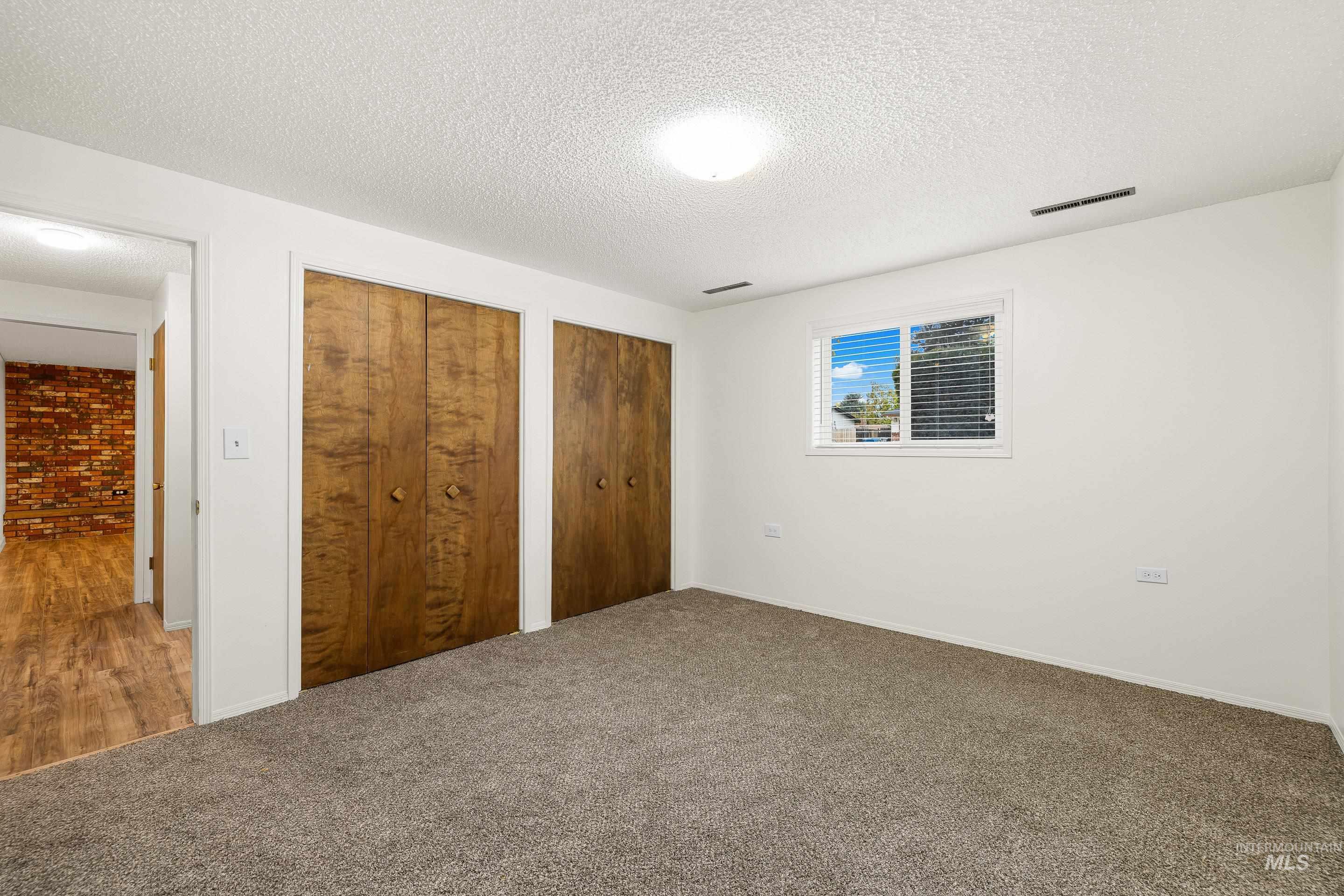 Unfurnished bedroom with multiple closets, a textured ceiling, and carpet