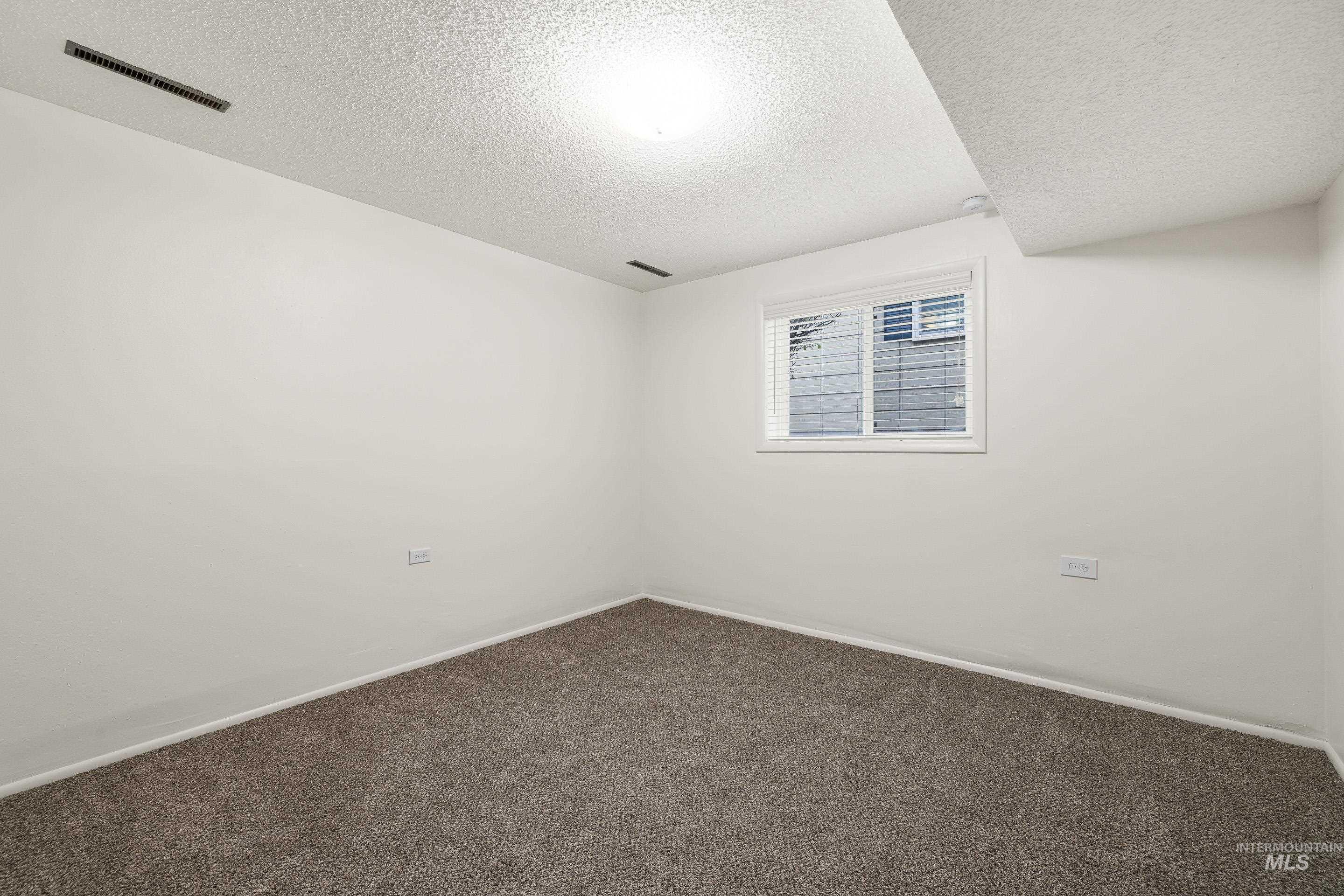 Spare room featuring a textured ceiling and carpet