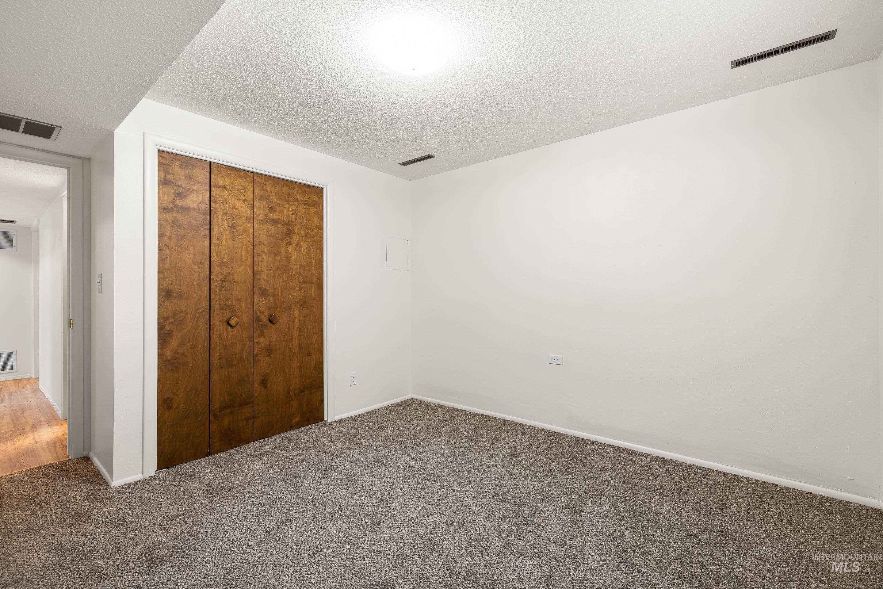 Unfurnished bedroom with a textured ceiling, a closet, and carpet flooring