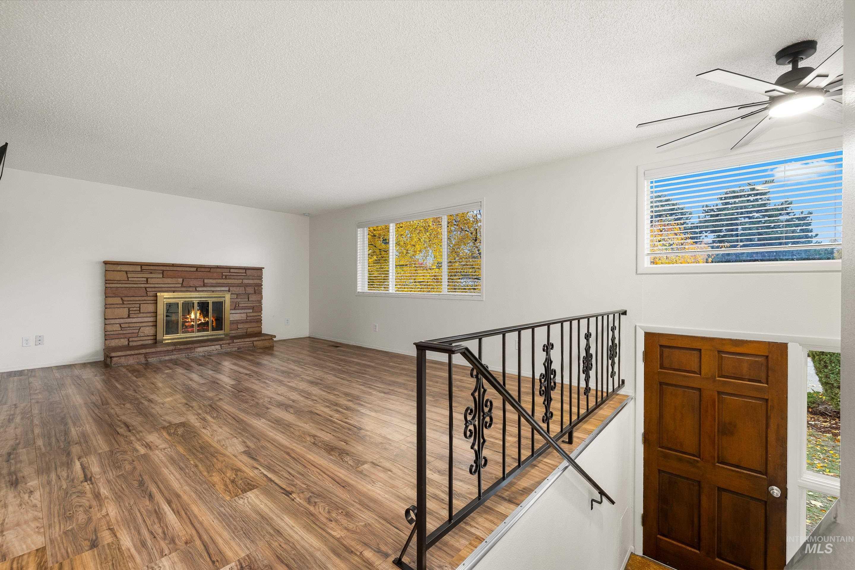 Living area featuring dark wood-style flooring, a textured ceiling, and a fireplace