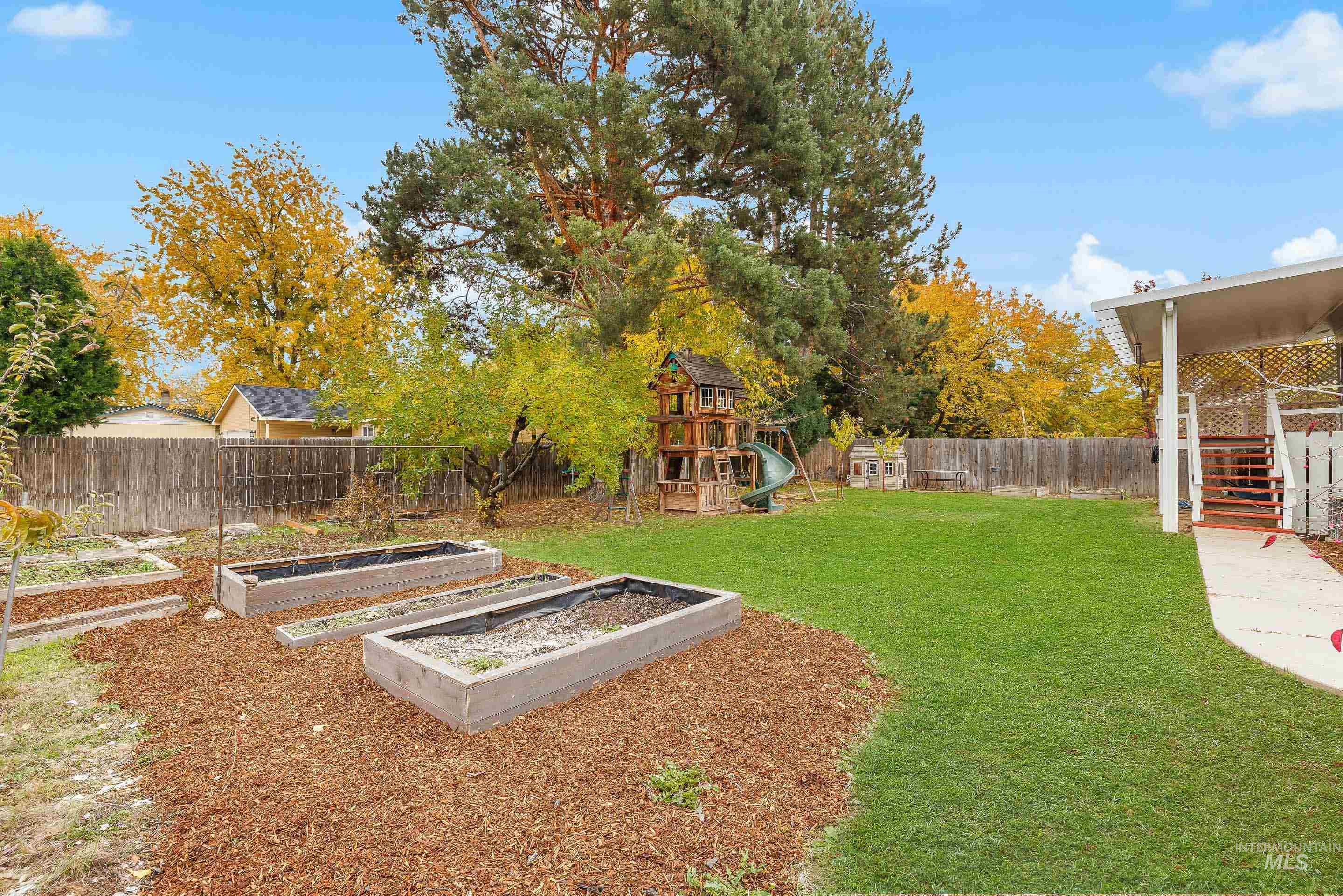 Fenced backyard with a garden and a playground