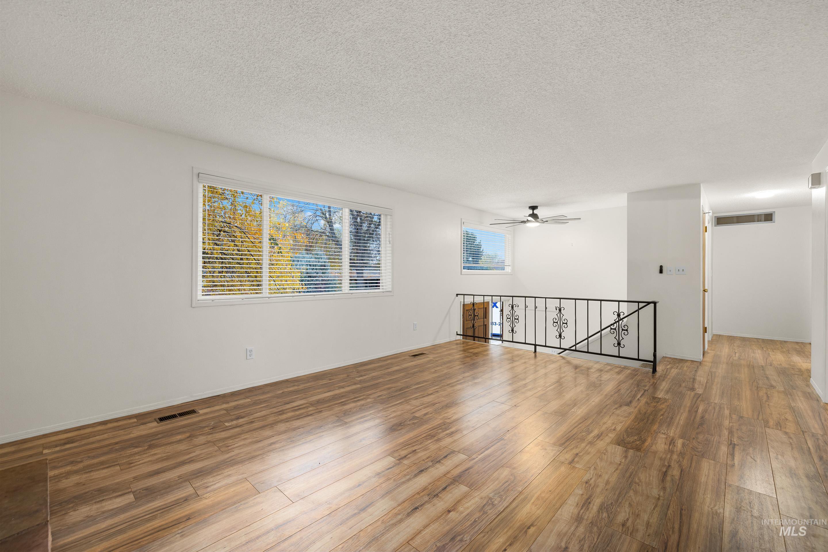 Unfurnished room with a textured ceiling, wood finished floors, and a ceiling fan