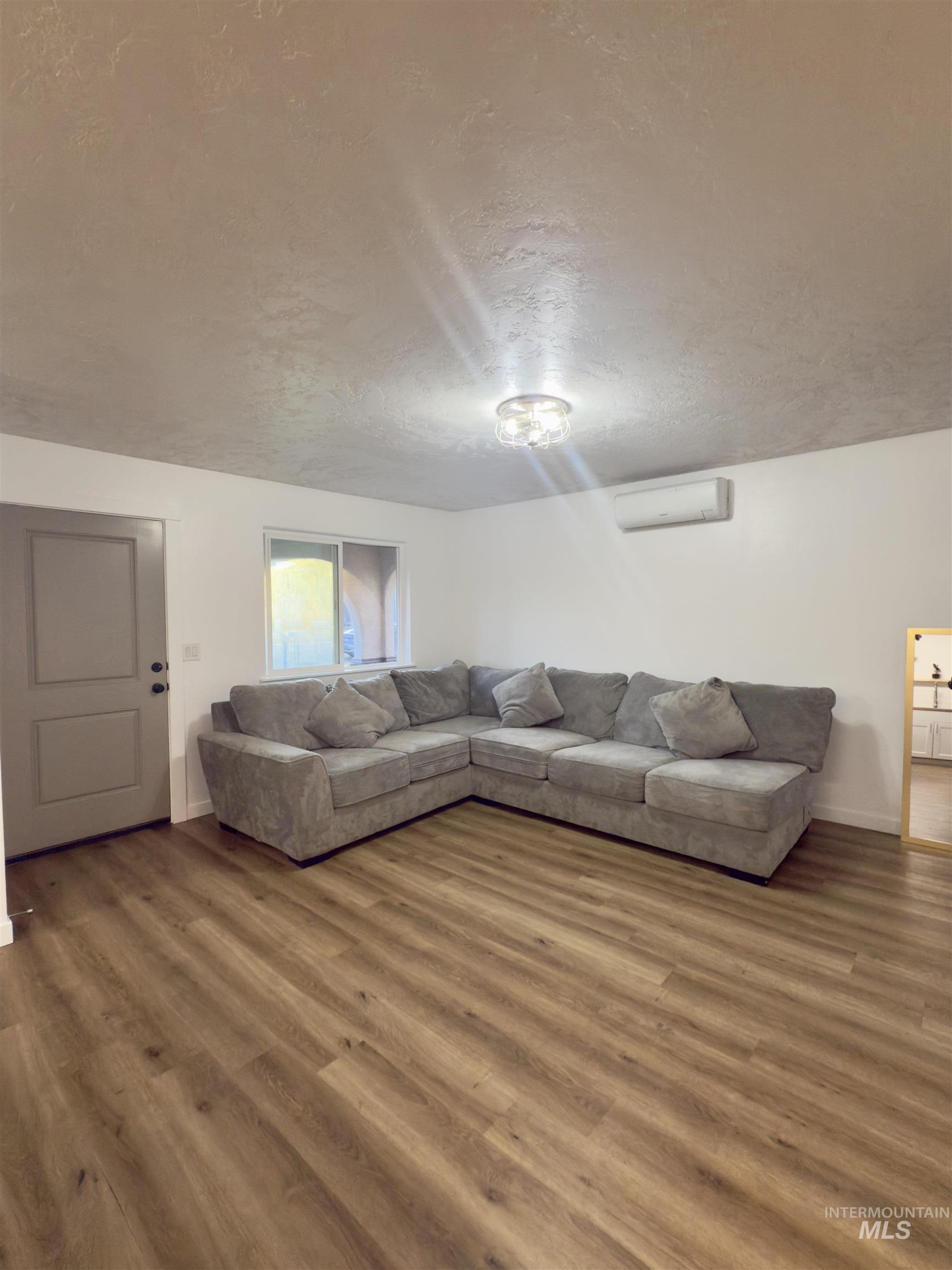 Living room with a textured ceiling and wood finished floors