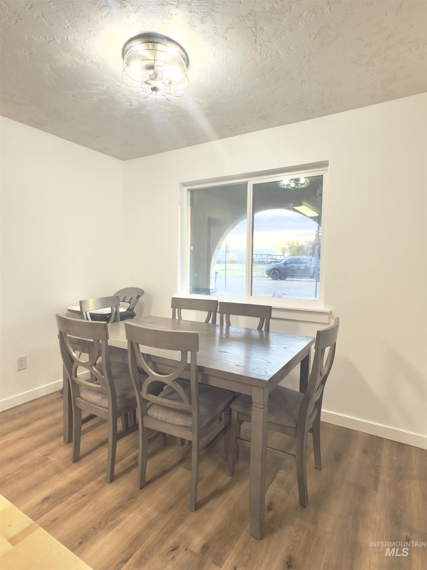 Dining space with a textured ceiling and dark wood-style flooring