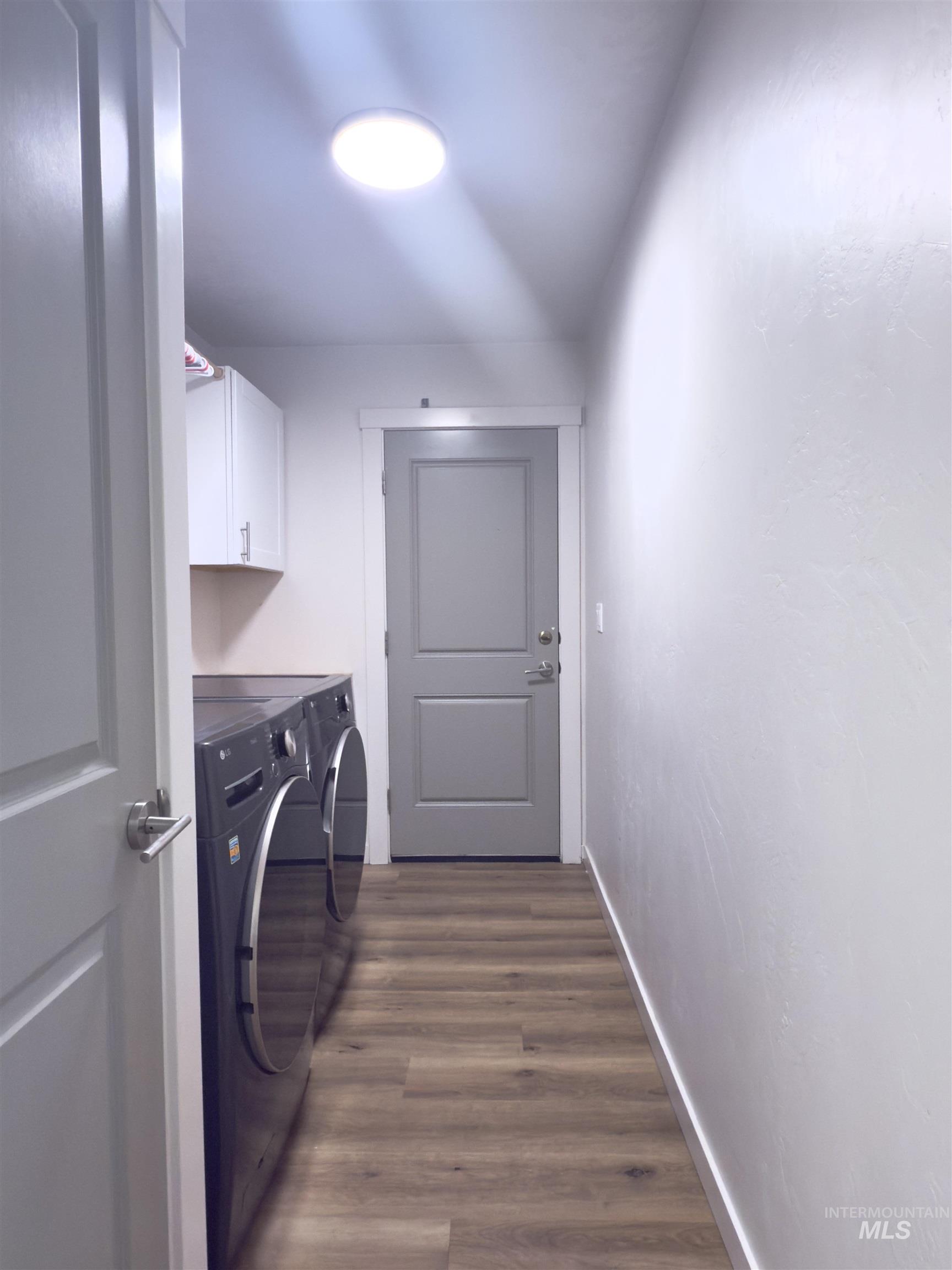 Laundry area featuring dark wood-style floors, cabinet space, and washer and dryer