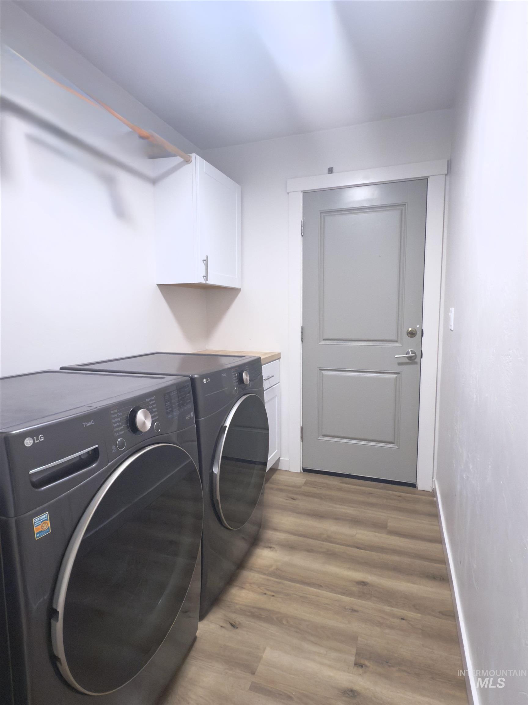 Washroom with light wood-style flooring, cabinet space, and separate washer and dryer
