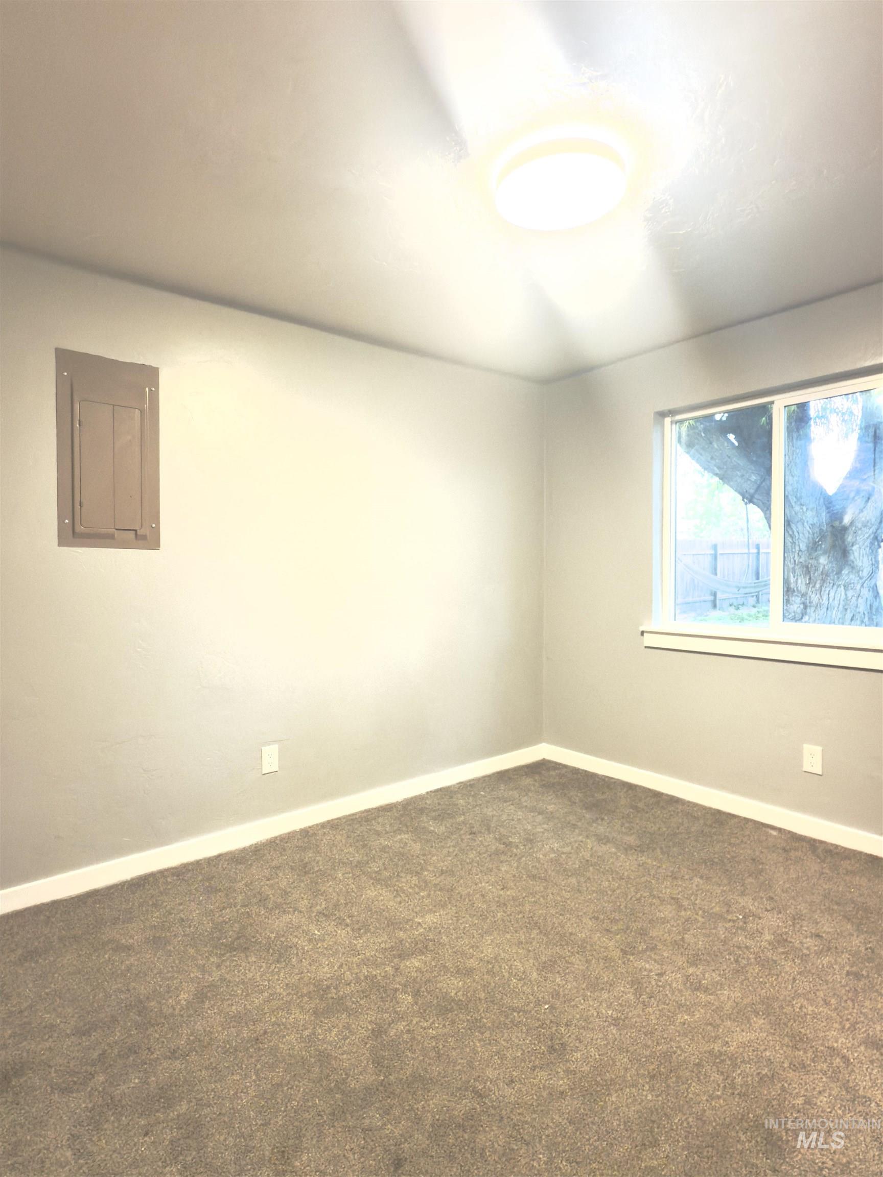 Spare room featuring dark colored carpet and electric panel