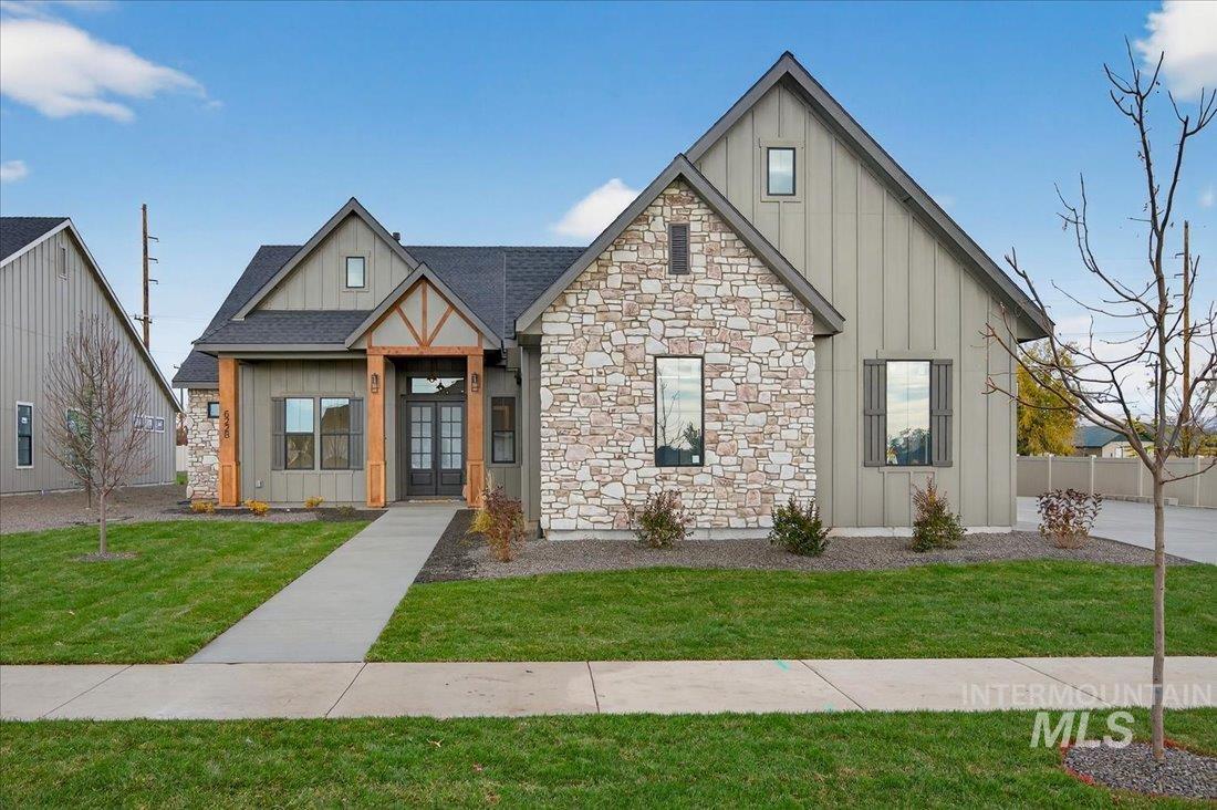 Modern farmhouse with board and batten siding, a shingled roof, and stone siding