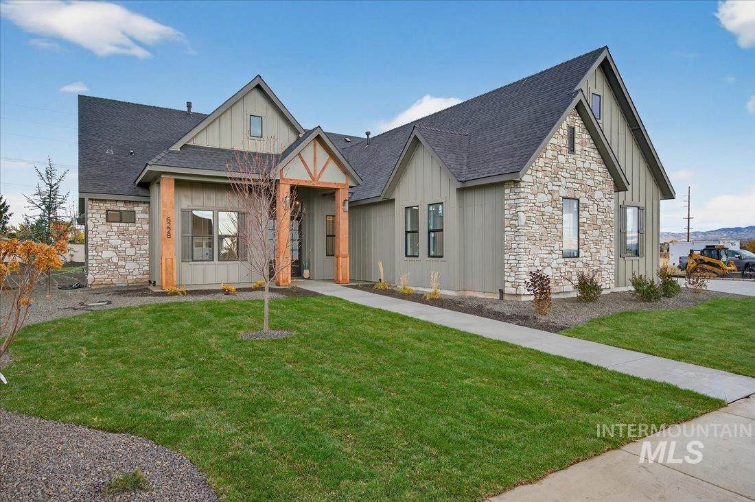 View of front facade with board and batten siding, stone siding, and roof with shingles