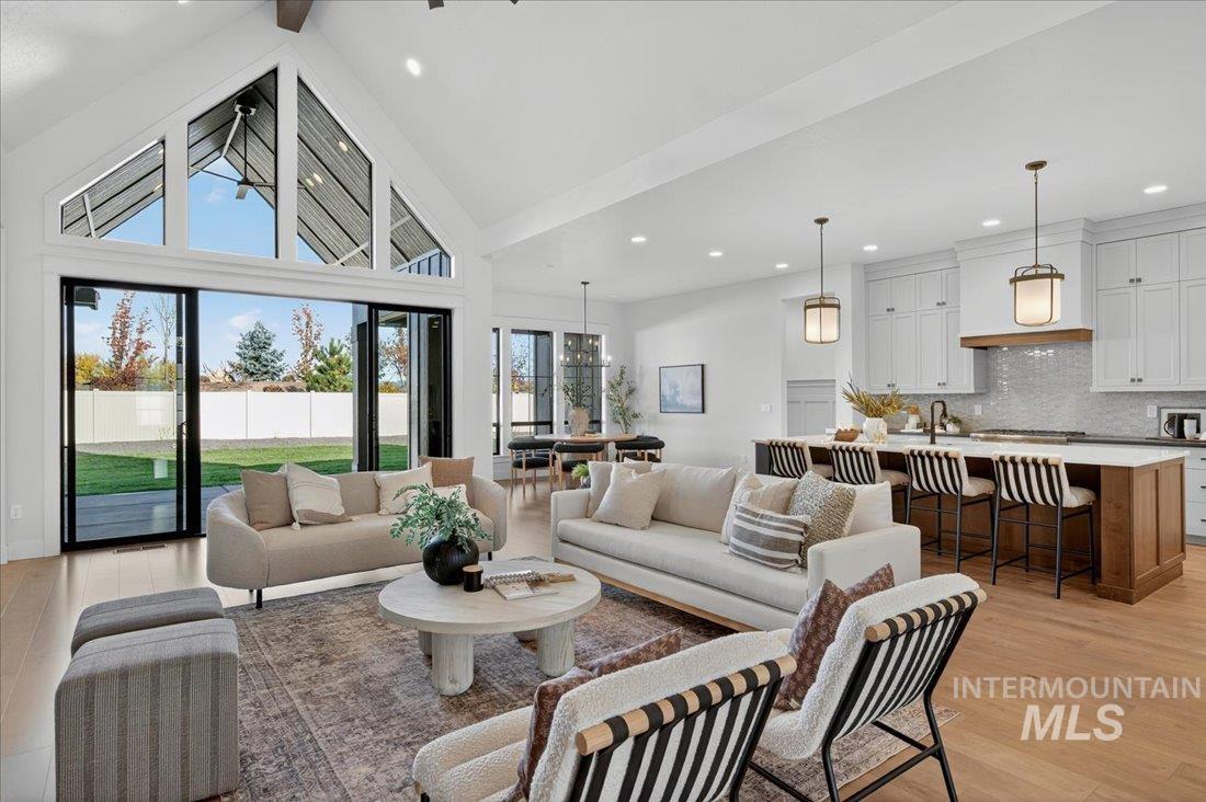 Living area featuring light wood finished floors, high vaulted ceiling, beamed ceiling, and recessed lighting