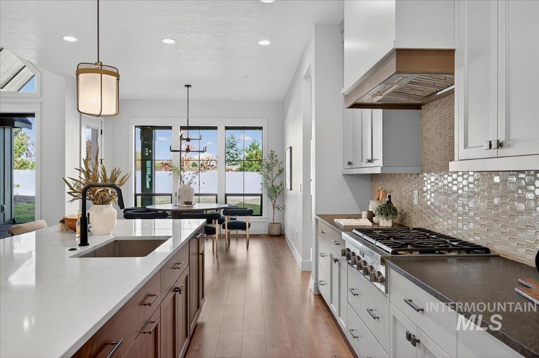 Kitchen featuring recessed lighting, dark stone countertops, decorative light fixtures, light wood-style floors, and stainless steel gas cooktop