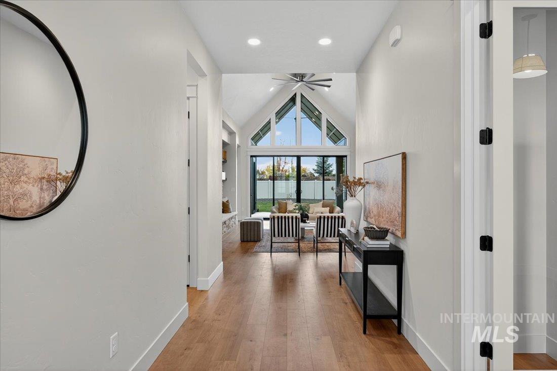 Hall with light wood-style floors, high vaulted ceiling, recessed lighting, and a water view