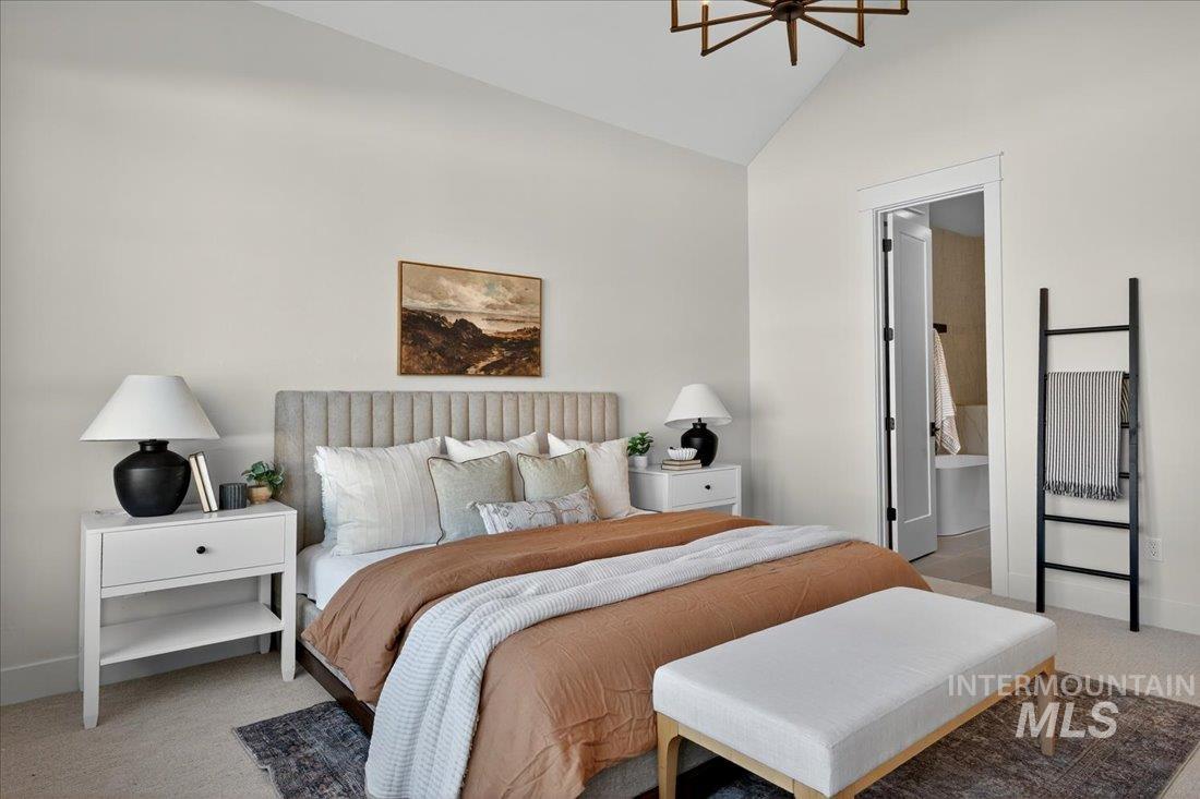 Bedroom with carpet flooring, ensuite bathroom, and high vaulted ceiling