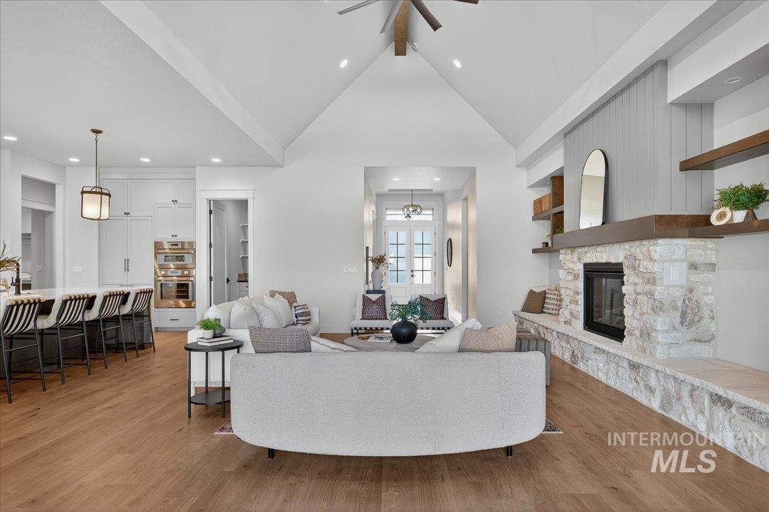 Living area featuring light wood finished floors, high vaulted ceiling, built in shelves, recessed lighting, and beam ceiling